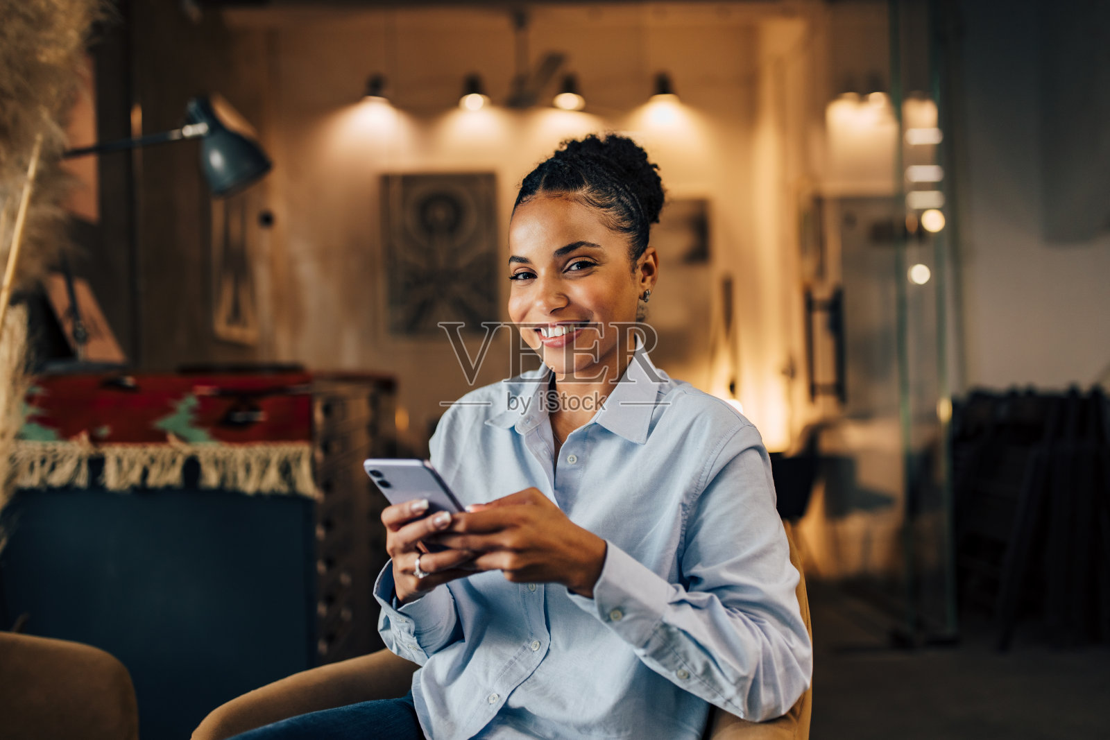 微笑的非洲女商人用智能手机对着镜头摆姿势。照片摄影图片