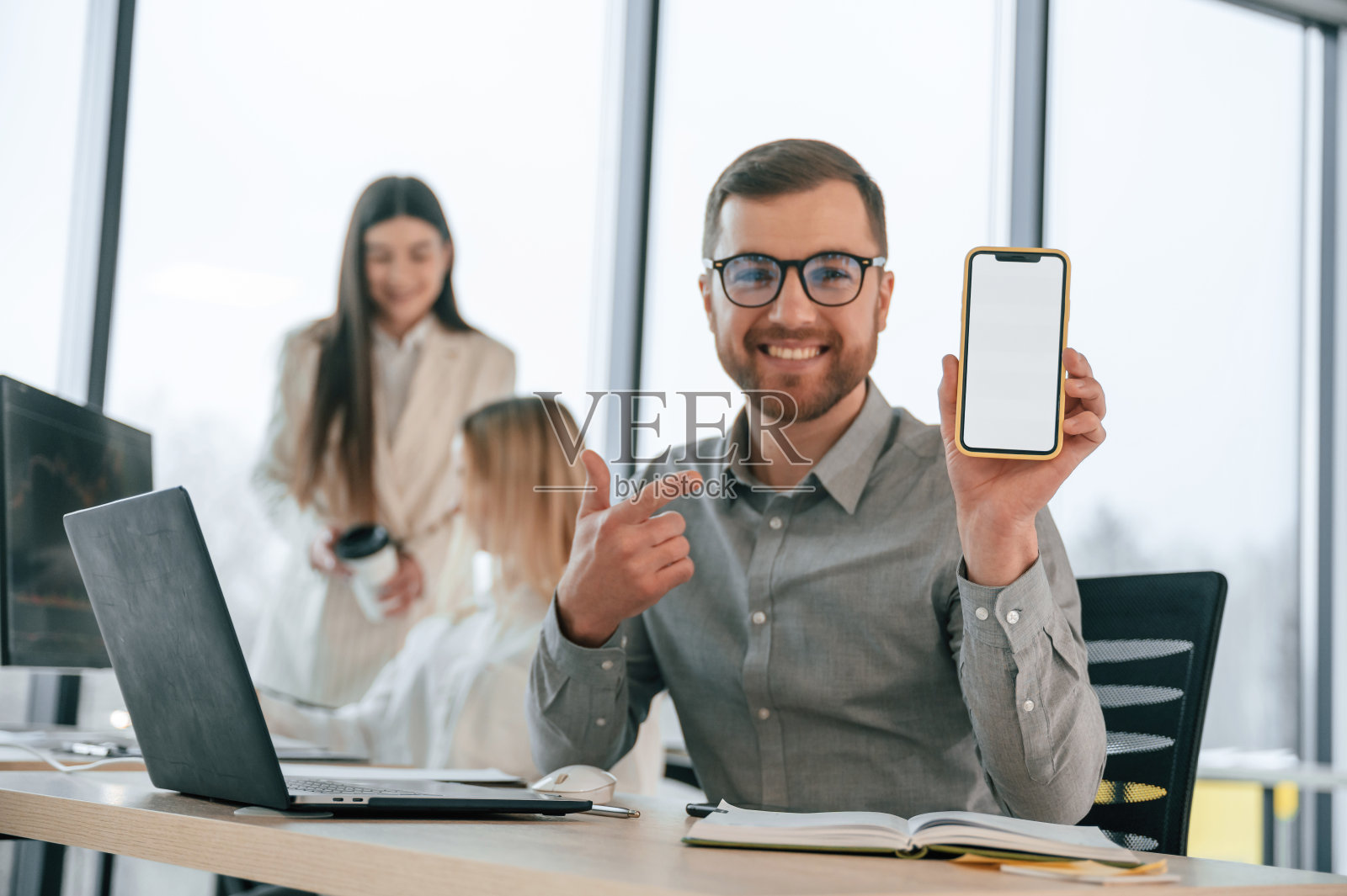 微笑着拿着智能手机。成功的团队都是在办公室里一起工作。商业概念照片摄影图片