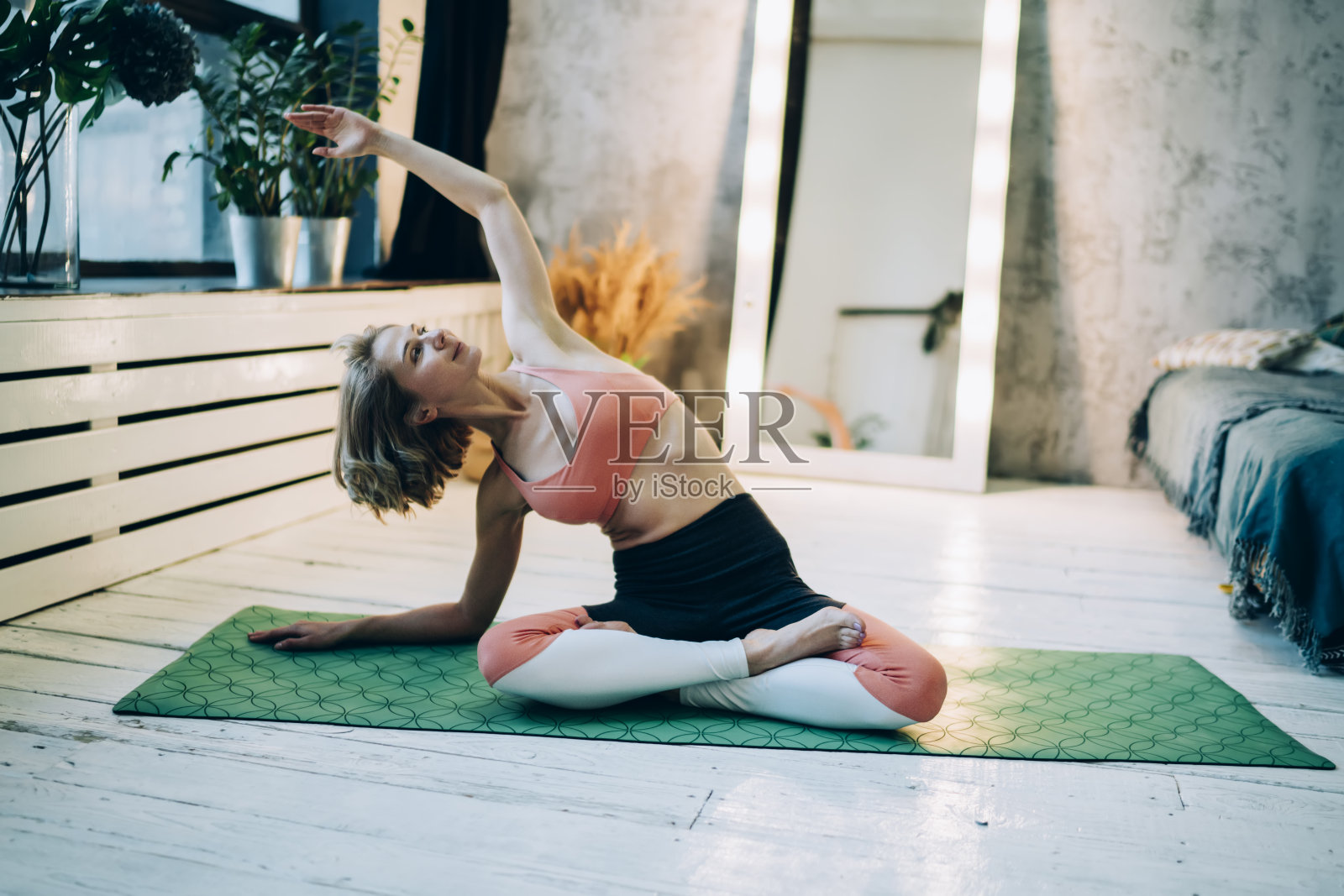 运动的年轻女子在运动服练习瑜伽坐在地毯上在家里照片摄影图片