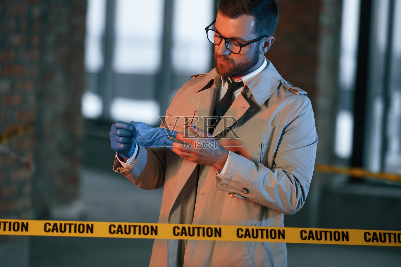 脱下手套。身穿外套的男侦探正在建筑工地的犯罪现场收集证据照片摄影图片