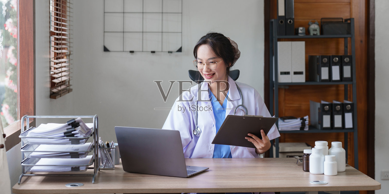 亚裔女医生在诊所的办公室里处理病人文件的肖像照片摄影图片