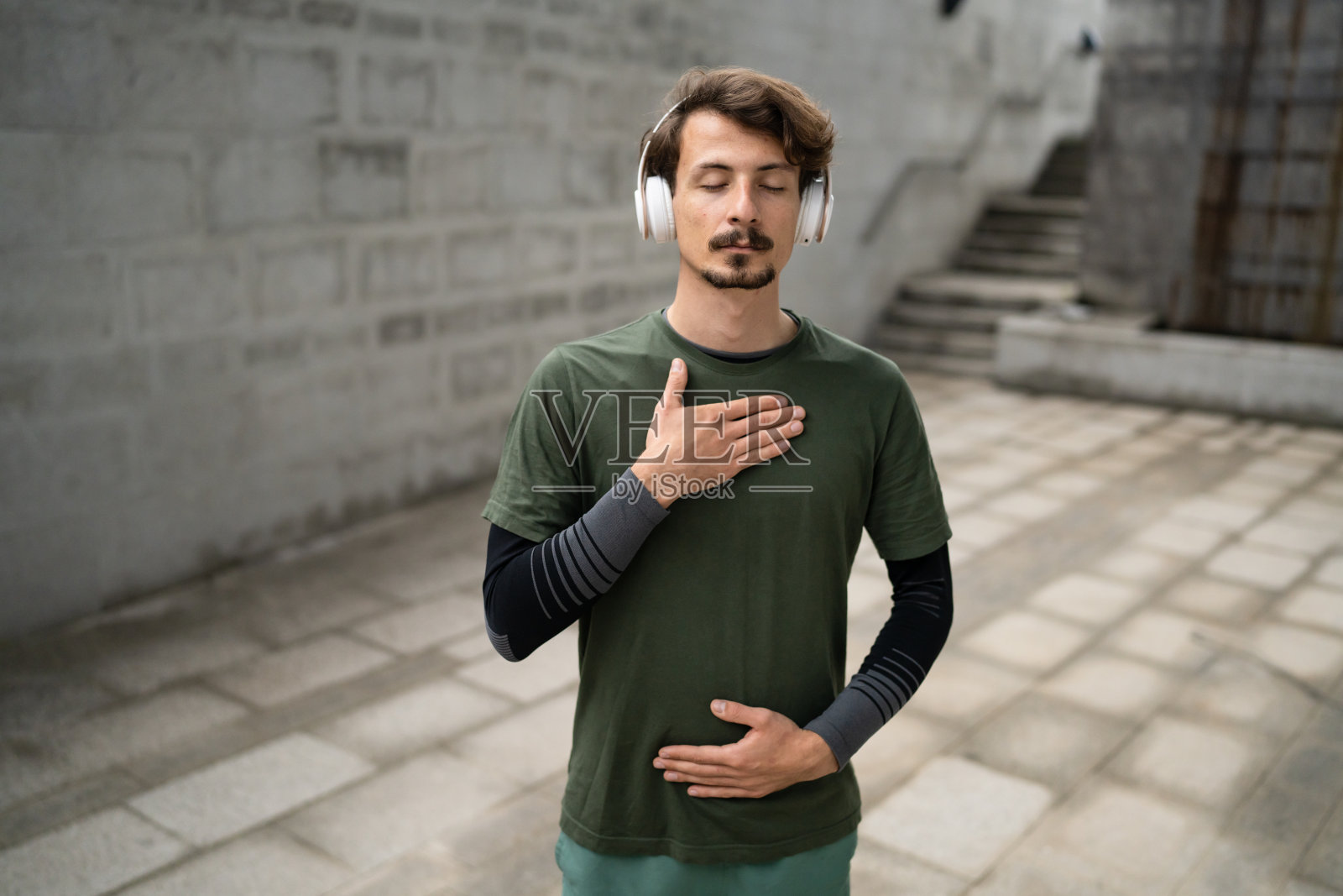 年轻的成年现代男子肖像站在户外，戴着耳机照片摄影图片