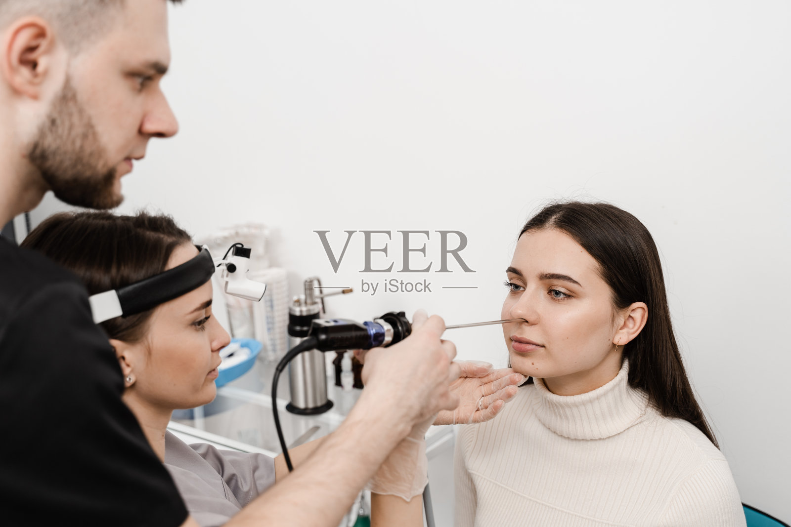 耳鼻喉科医学生鼻内窥镜实习。用鼻镜进行鼻镜检查。耳鼻喉科医生同事用大灯治疗鼻女病人。照片摄影图片