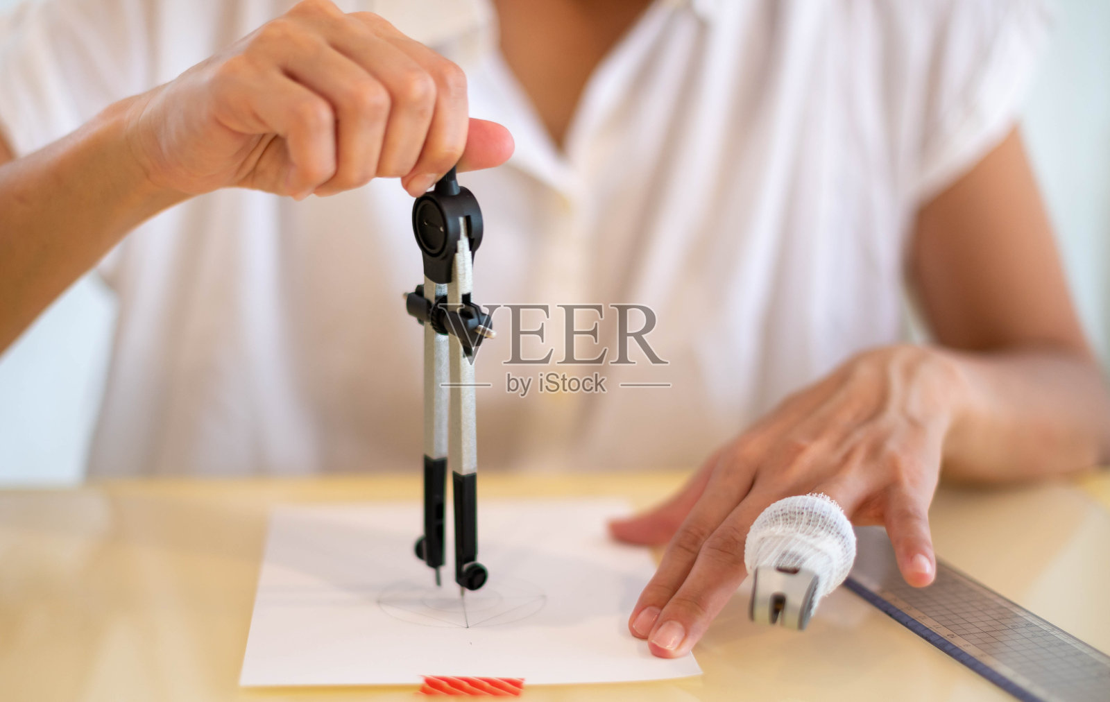 女性用测量好的圆准备在空白白纸上画草图。照片摄影图片