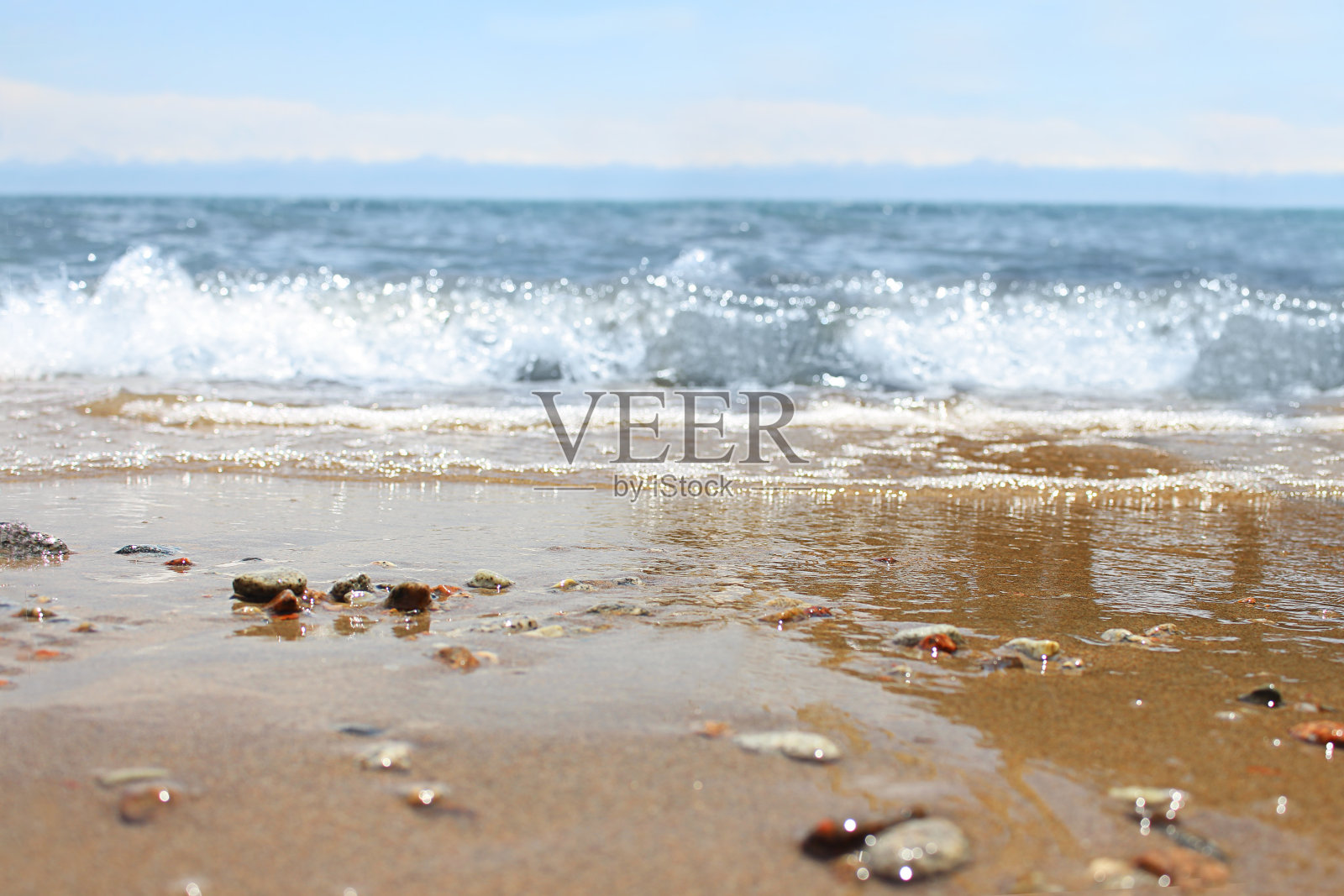 散焦海滩与模糊的波浪和潮湿的沙子与鹅卵石在蓝天上。大海，大海的背景。度假户外和旅行假日冒险概念照片摄影图片