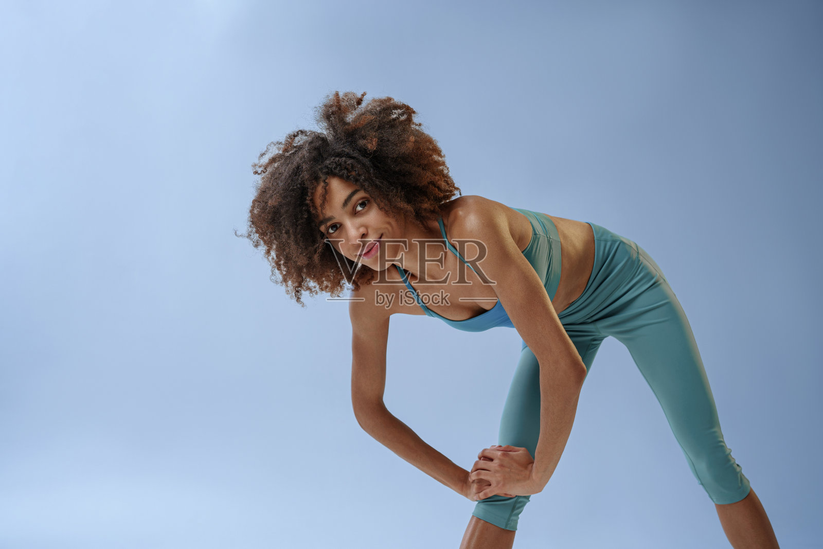 近距离运动的女人在工作室背景上做伸展运动，看着相机照片摄影图片