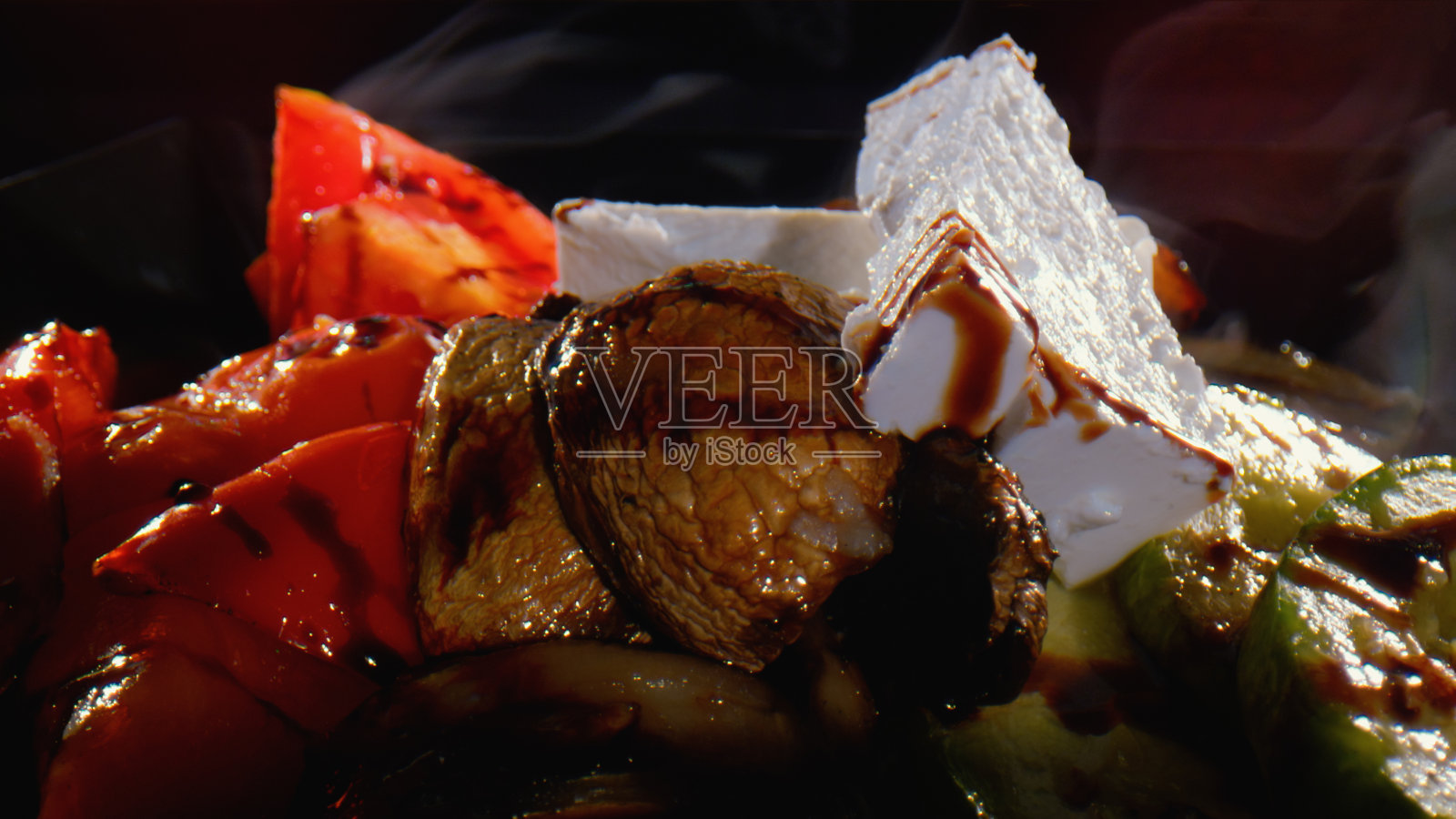 烤土豆配蕃茄片，小胡瓜和羊乳酪淋上酱汁-近景照片摄影图片