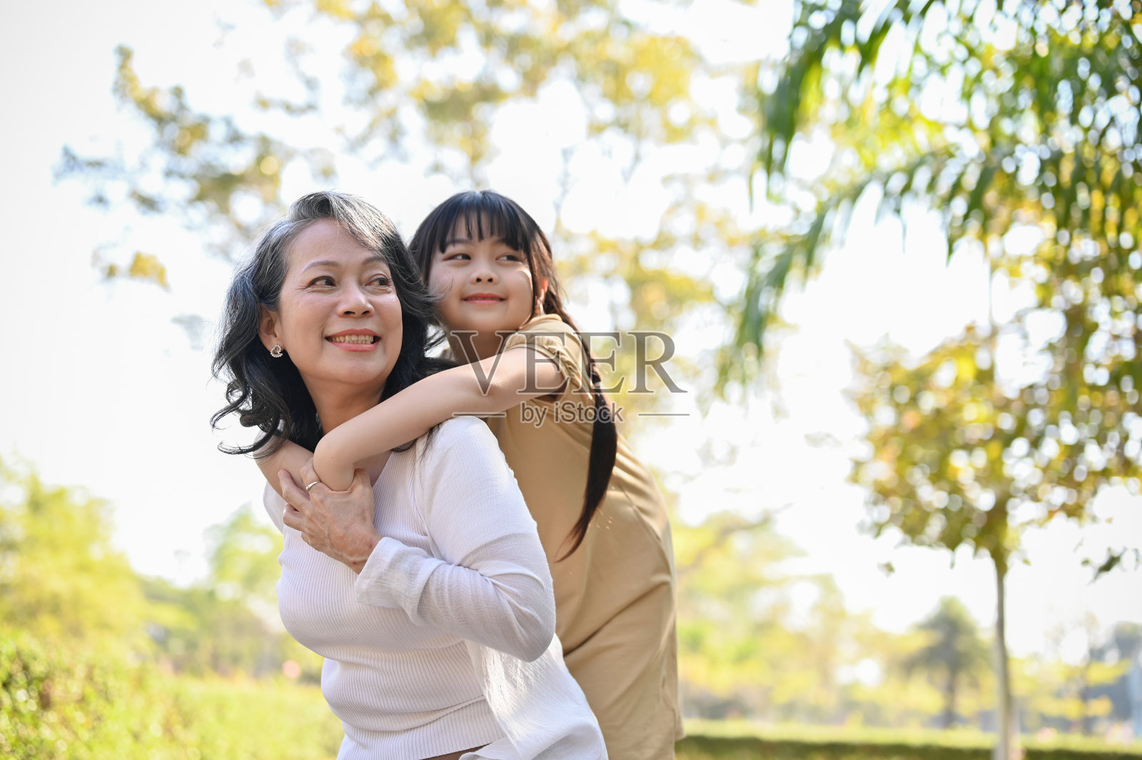 快乐的亚洲奶奶和她可爱的孙女在公园里，小猪背，快乐的家庭时光照片摄影图片