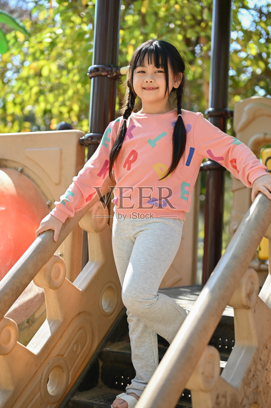 漂亮的亚洲女孩在操场上的设备，在城市公园的操场上玩。照片摄影图片