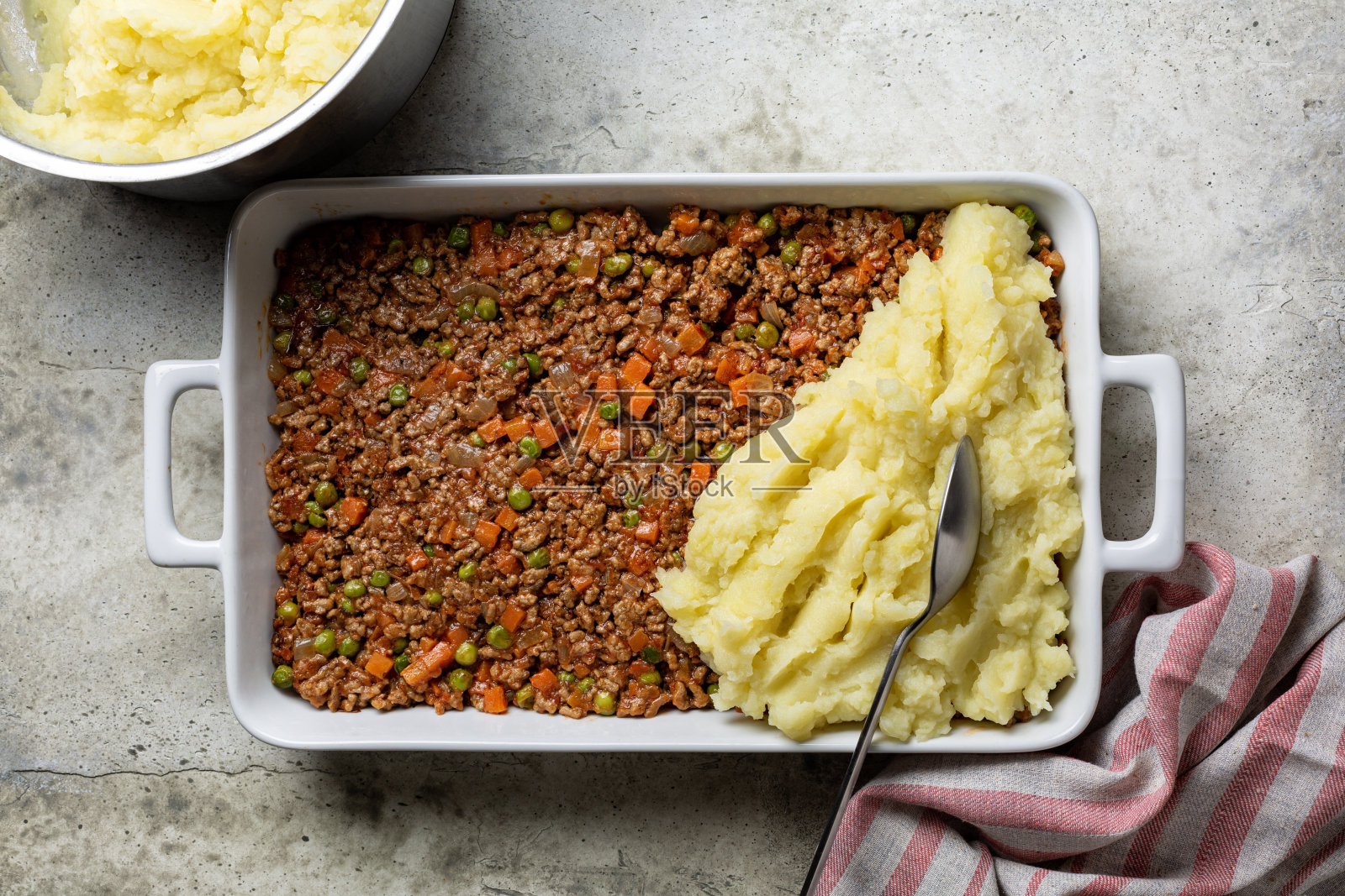 烹饪牧羊人派、乡村派或法国版hachis Parmentier的过程。烤前用土豆泥把切碎的牛肉和蔬菜一起煮熟。照片摄影图片