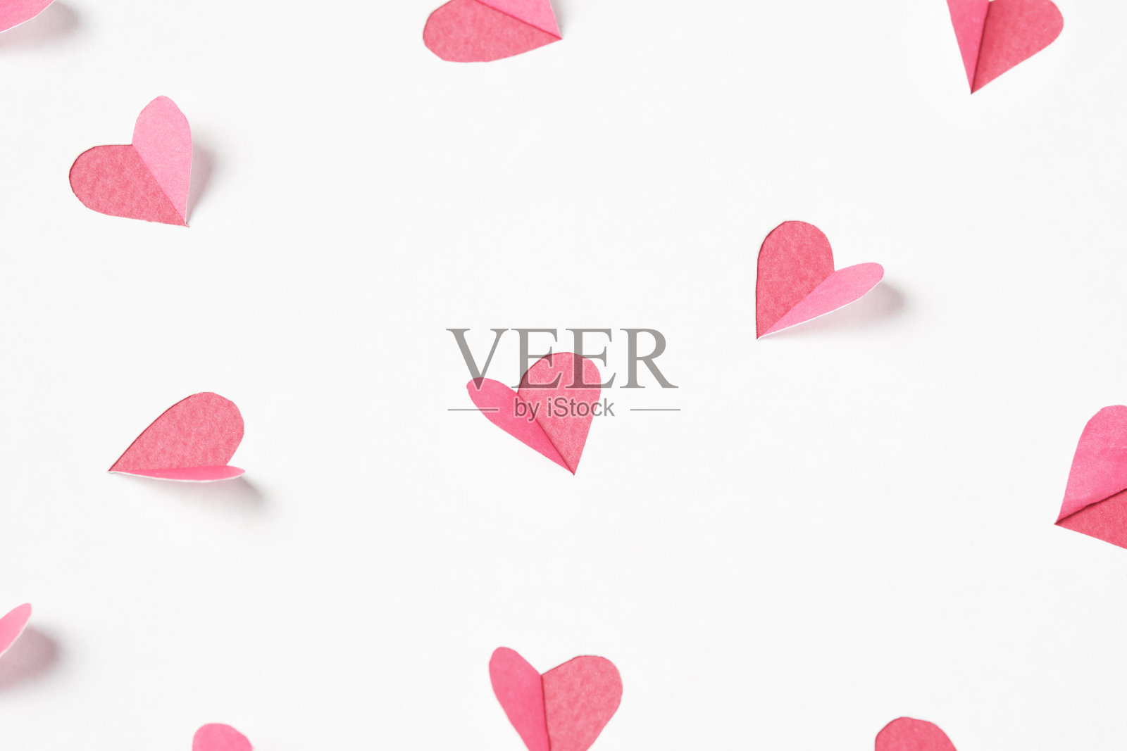 从白纸上剪出粉红色的心。情人节的节日背景。照片摄影图片