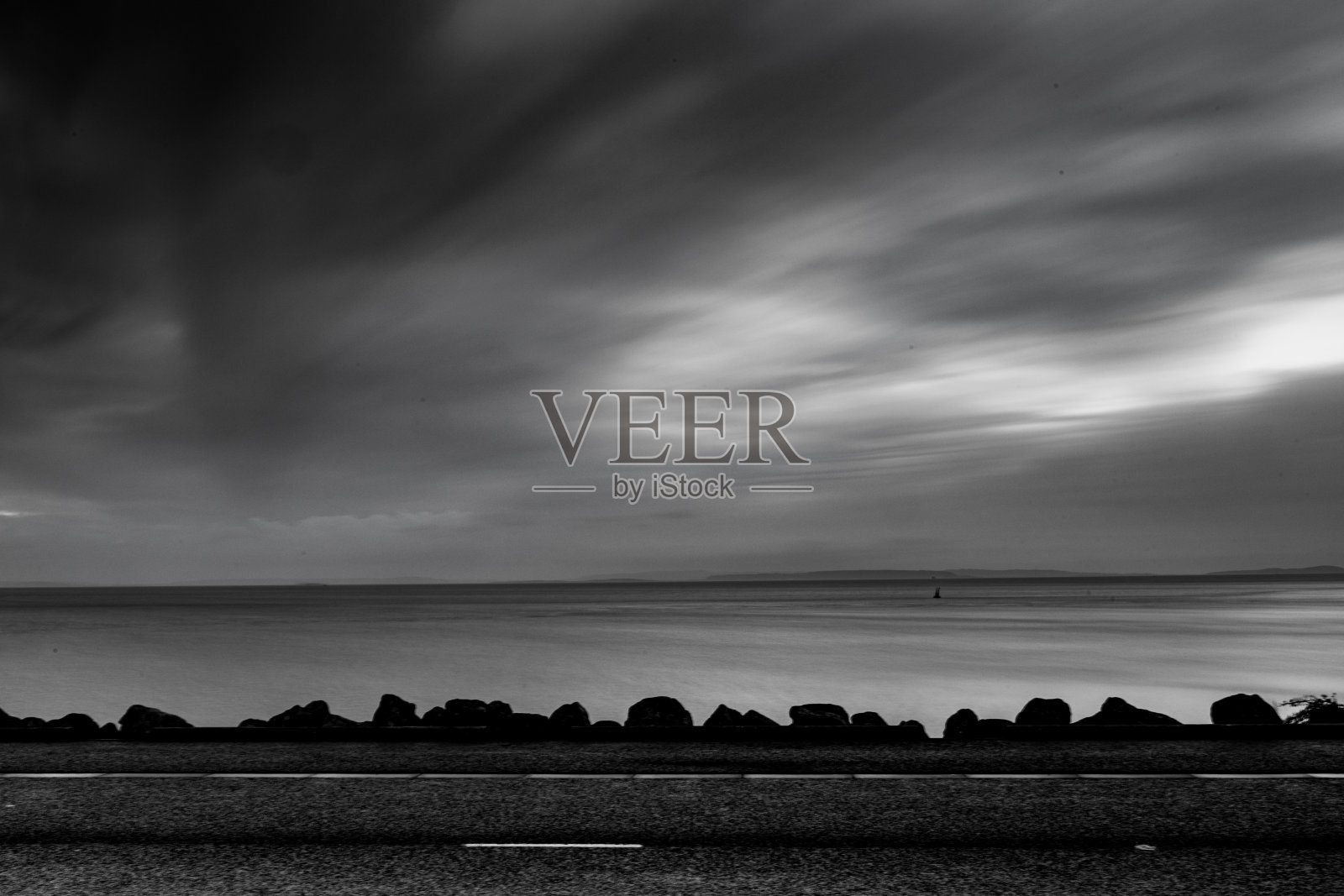 在多云的天空下的海滨的灰度镜头照片摄影图片