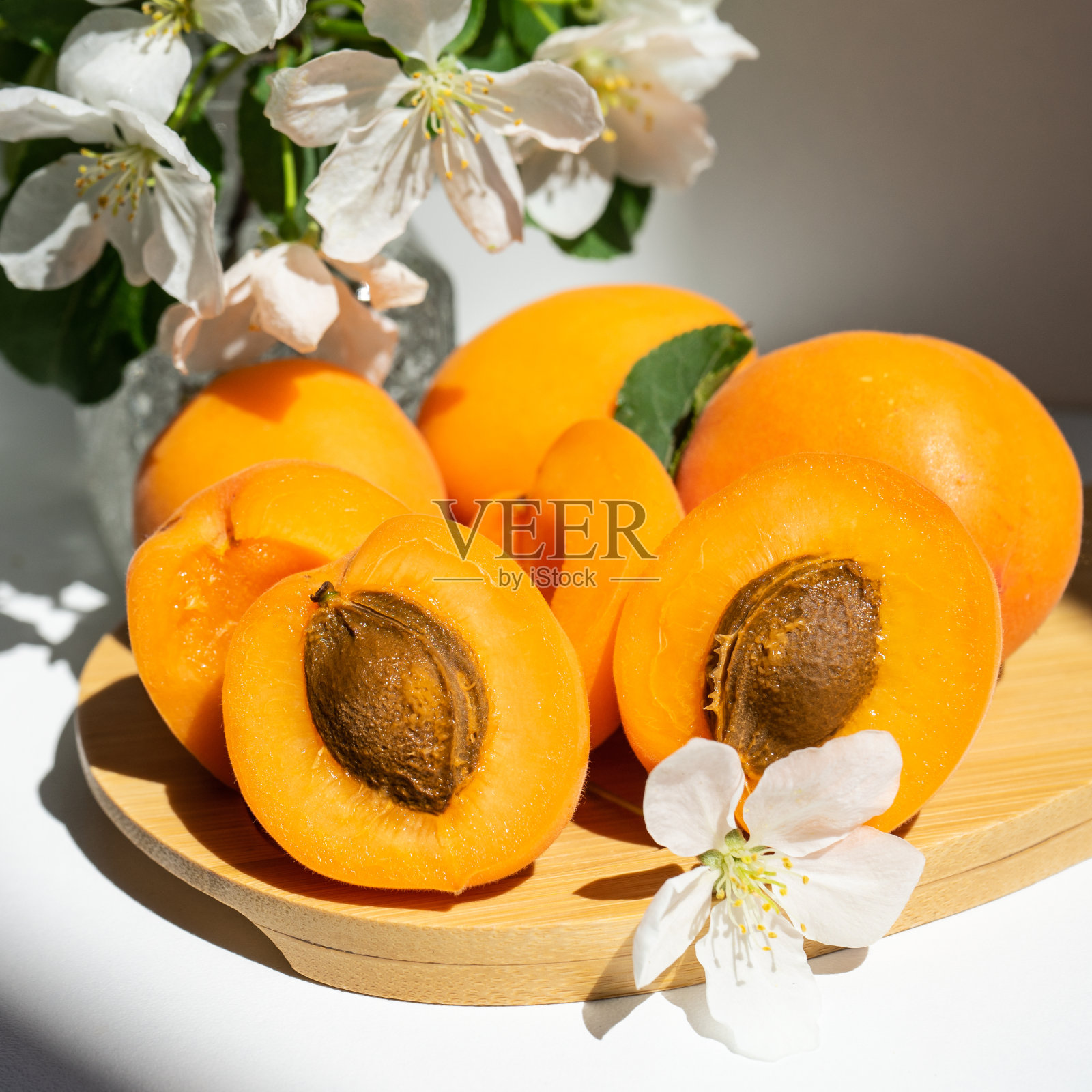 多汁的成熟杏子，整块切成块。杏和白花的静物。有选择性的重点。春季静物照片摄影图片