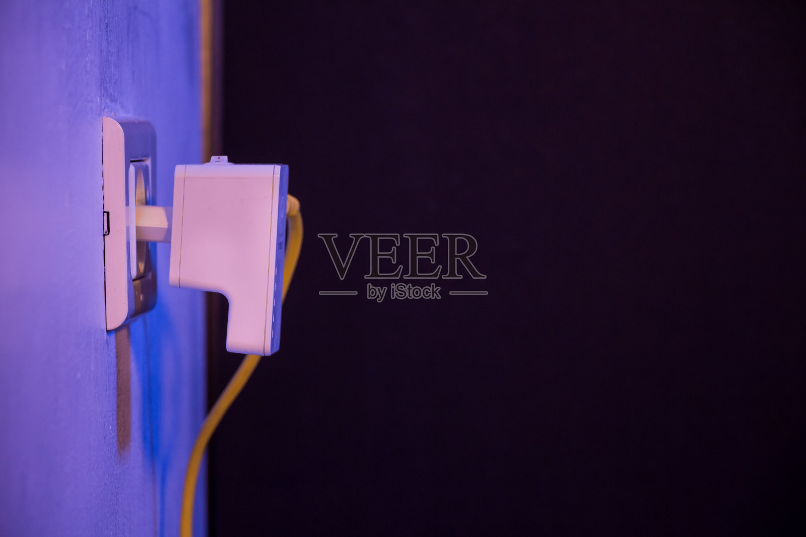 WiFi扩展器在墙上的电源插座上，并插入以太网电缆照片摄影图片