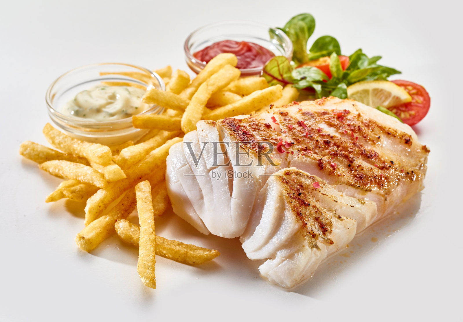 白色底色配以蔬菜和酱汁的鱼片和炸薯条，令人食欲大开照片摄影图片