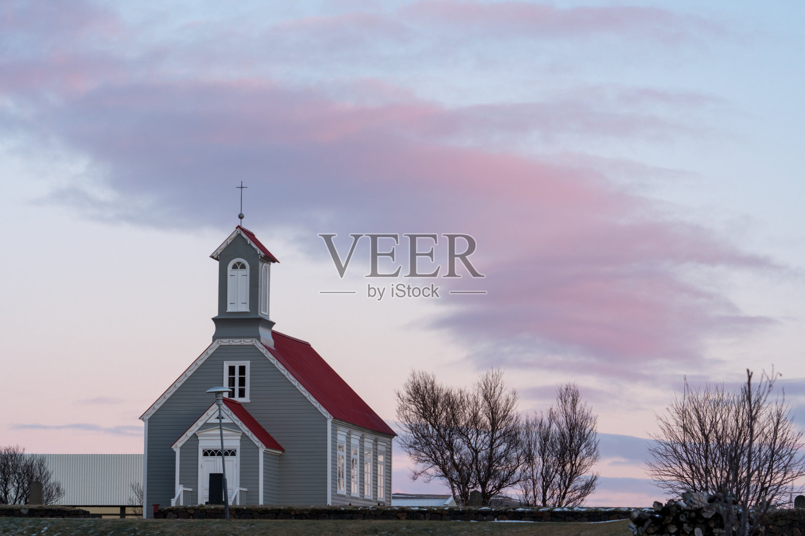 在冰岛西部的雷克浩特，粉色天空映衬下的古老木制教堂(雷克浩特教堂)照片摄影图片