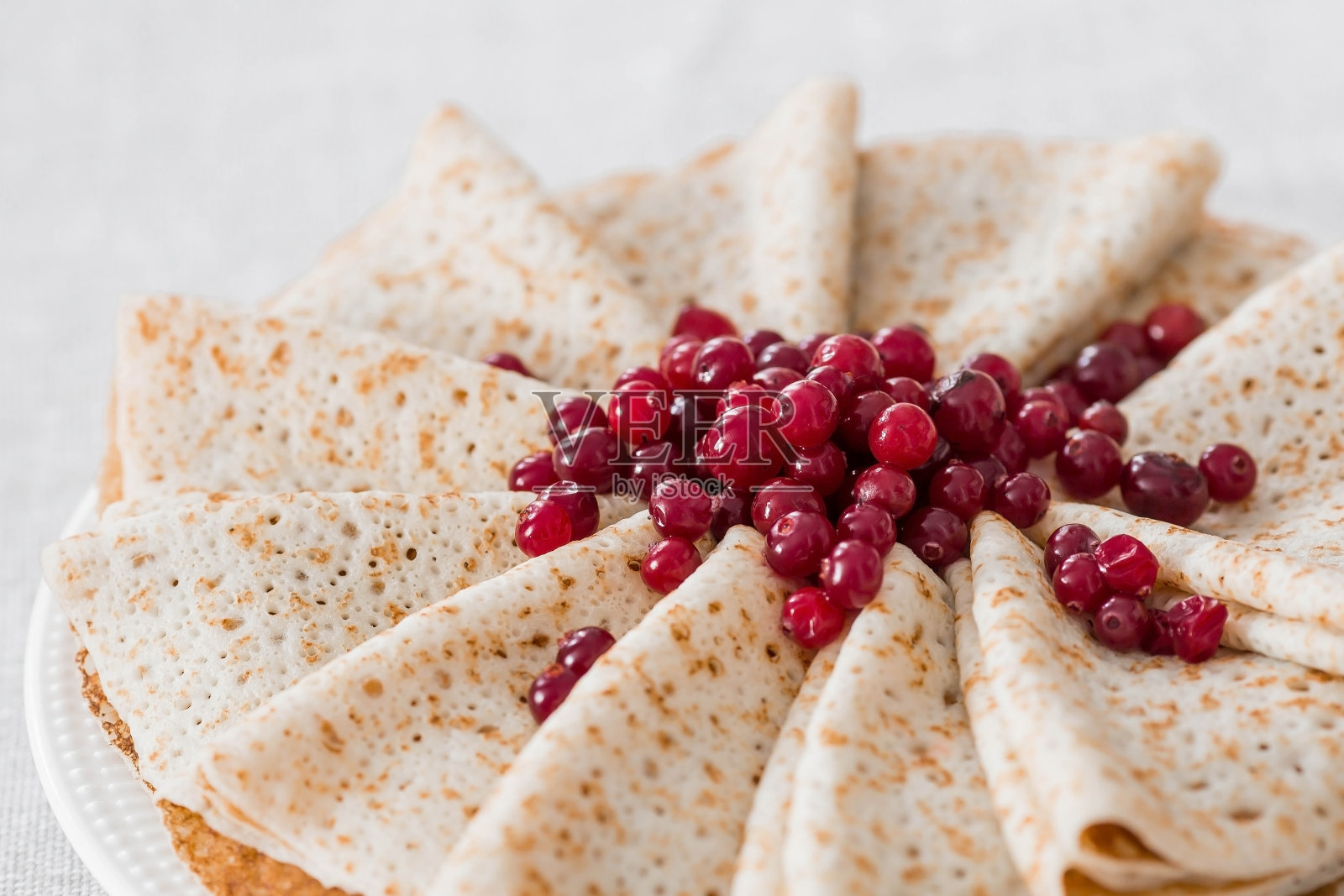 俄罗斯的传统。俄罗斯节日Maslenitsa。静物配上一杯茶，一叠北方蔓越莓煎饼，桌上放着几块黄油。照片摄影图片