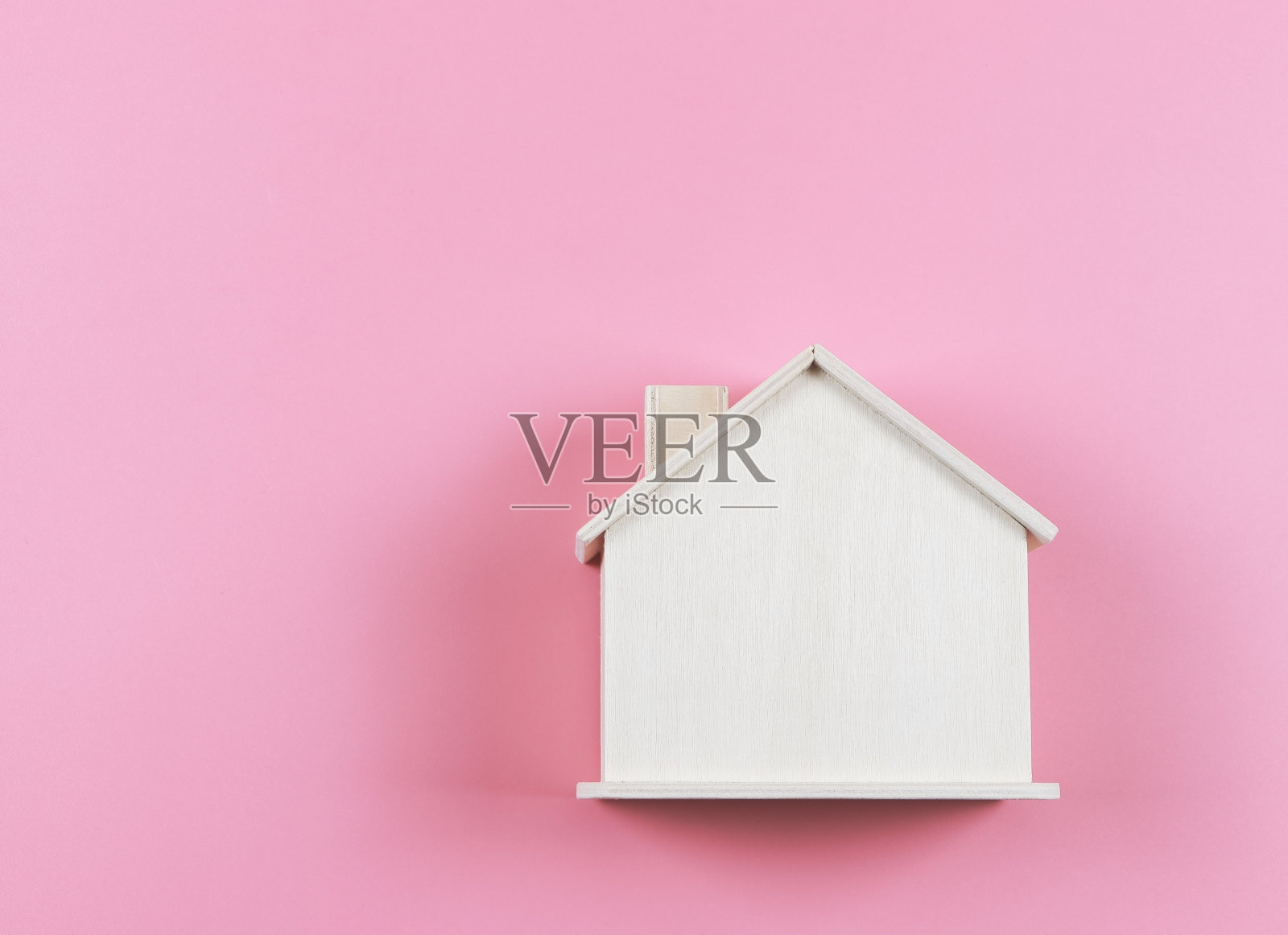 粉色背景上的木质模型房子。照片摄影图片
