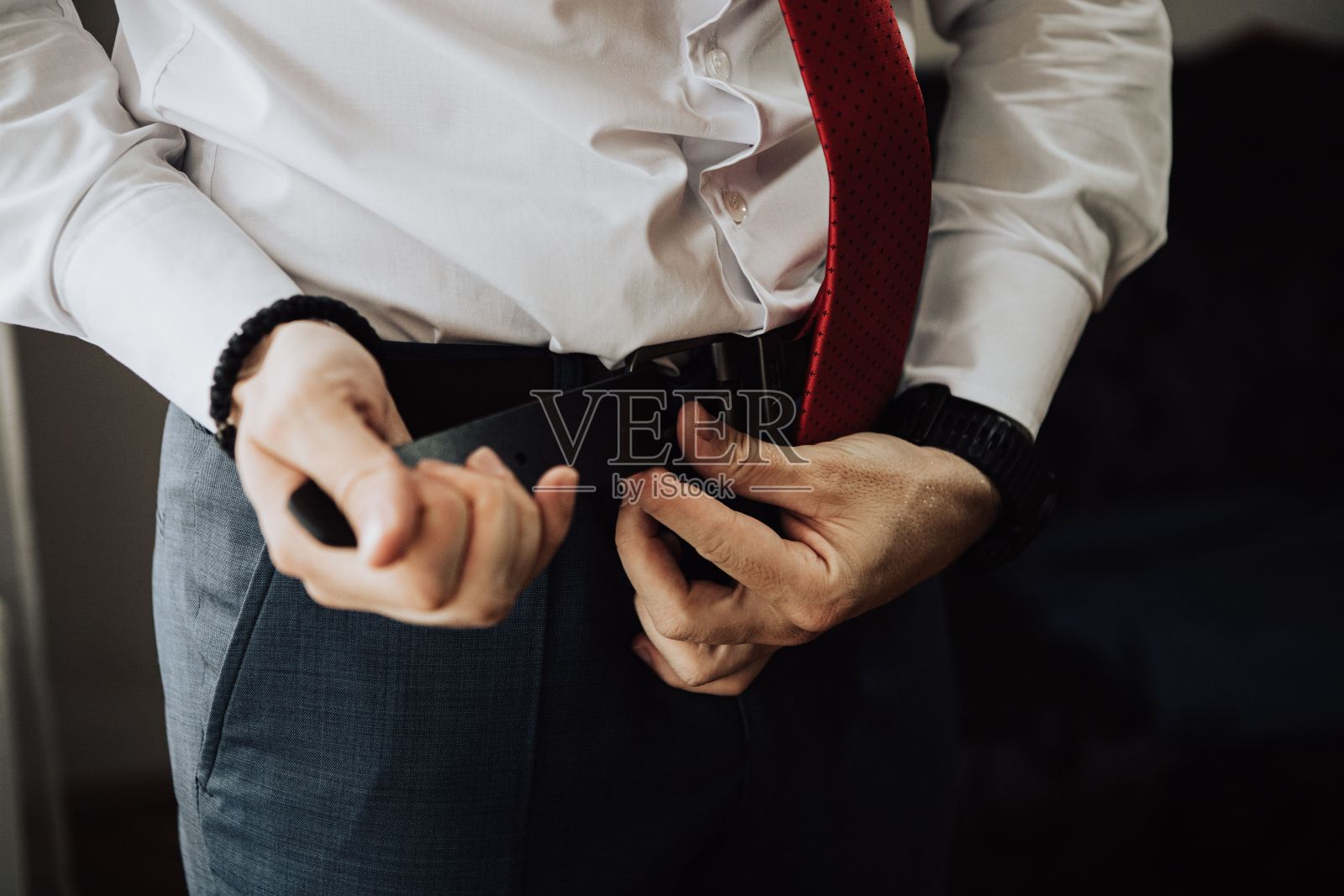 一个穿着白衬衫，打着红领带，系着腰带的男人照片摄影图片