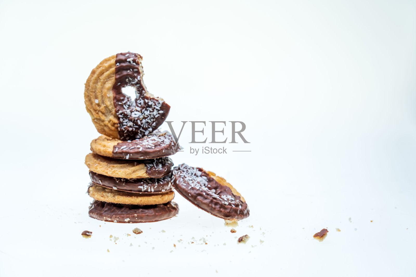 一个吃了一半的饼干特写，白色背景上有椰子和巧克力照片摄影图片