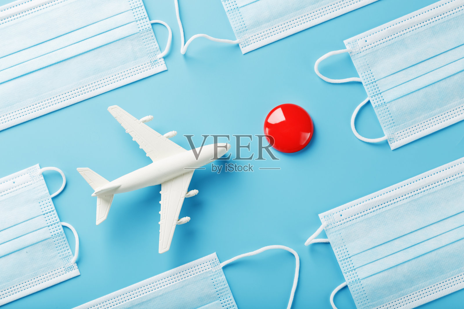 一架白色的玩具飞机和蓝色背景上的防护面具，目的地是一个红点。照片摄影图片