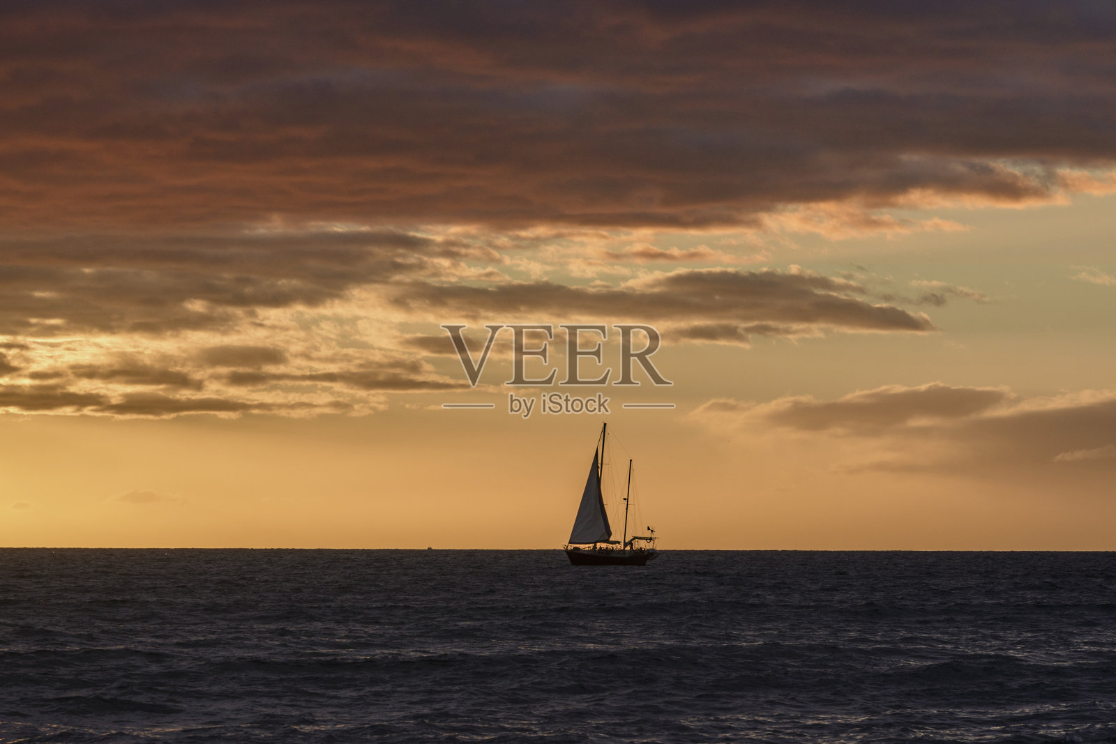 日落时分，帆船在海上航行照片摄影图片
