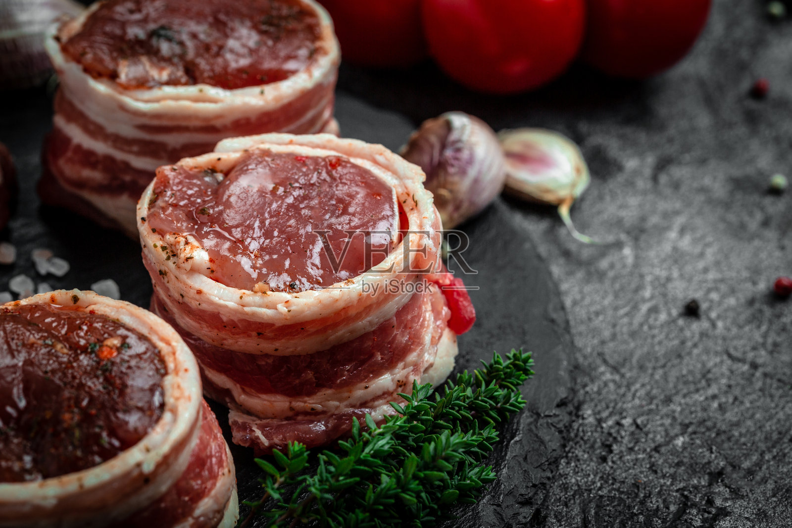 生菲力牛排金属盘加胡椒和盐，菲力牛排。牛肉里脊肉用培根和百里香包裹，深色背景。俯视图照片摄影图片