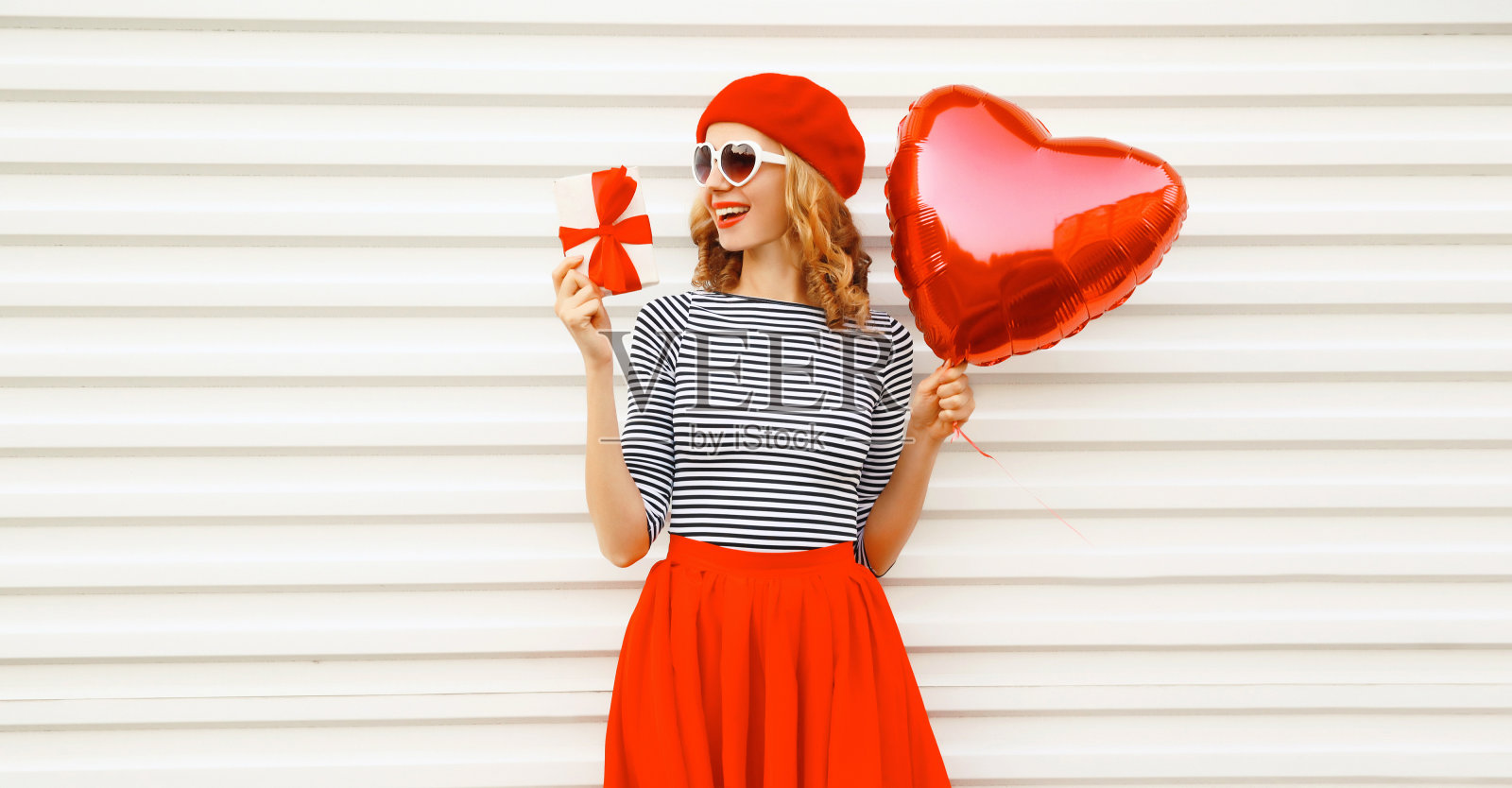 快乐微笑的女人肖像红色心形气球和礼盒穿着贝雷帽和白色背景的裙子照片摄影图片