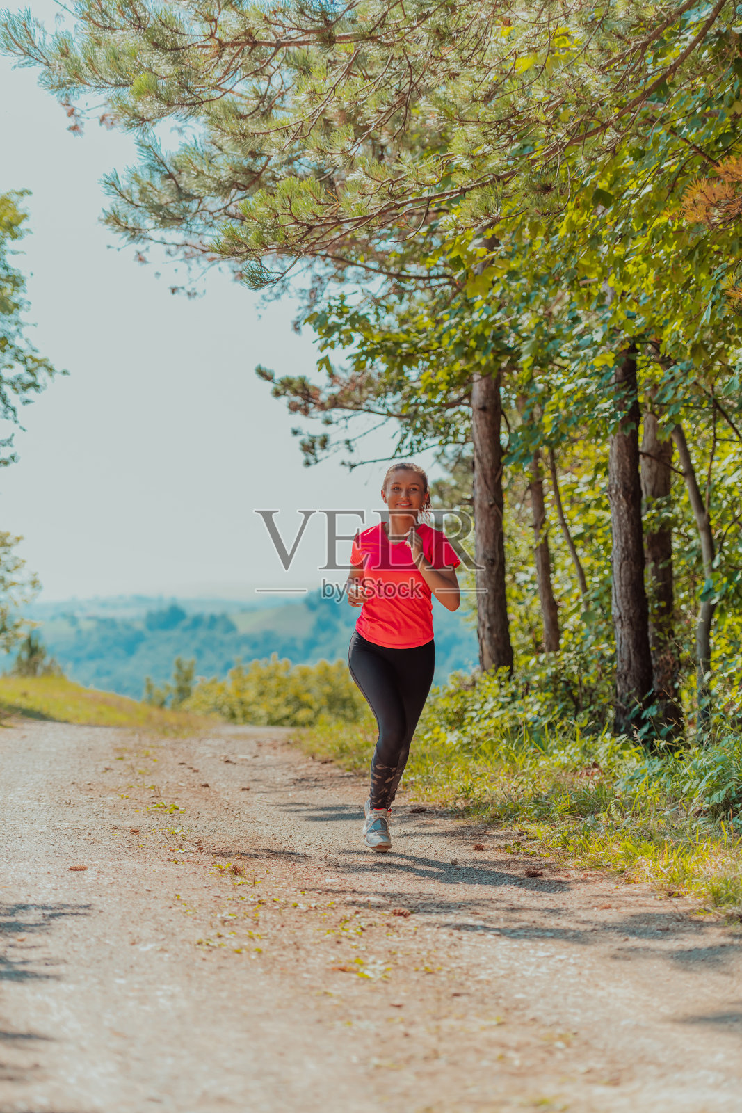 年轻快乐的女子享受健康的生活方式，在乡村道路上慢跑，穿过美丽的阳光森林，锻炼和健身的理念照片摄影图片