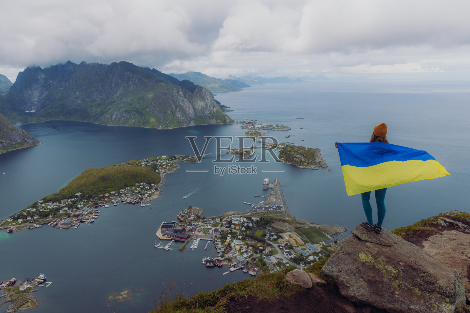 从莱茵布林根山顶俯瞰罗弗敦群岛的一位手持乌克兰国旗的妇女的侧视图照片摄影图片
