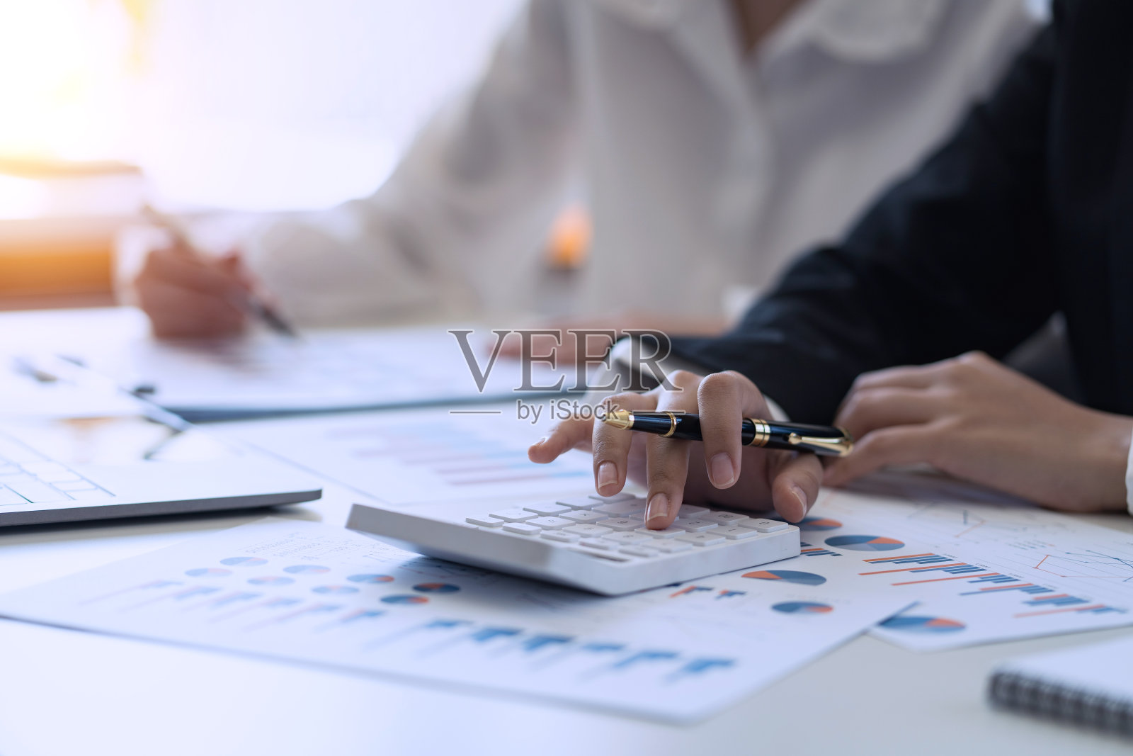 商务人士在商务会议上指着图表和使用计算器。照片摄影图片