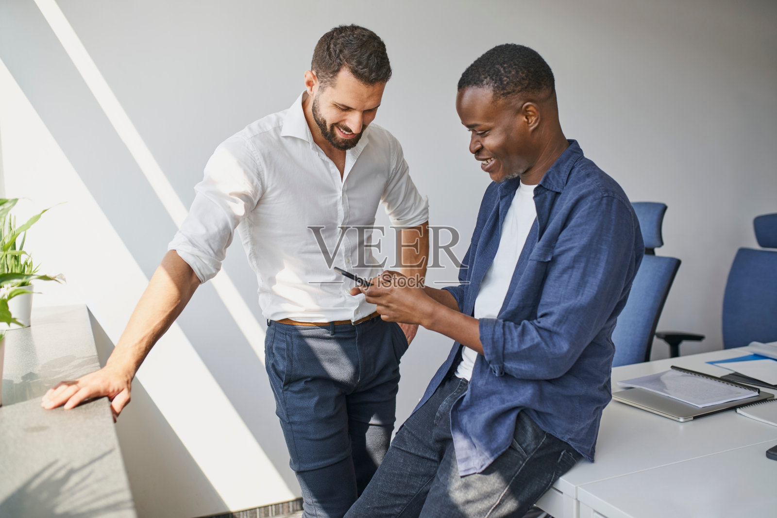 两个在办公室的男人在电话里分享一些趣事照片摄影图片