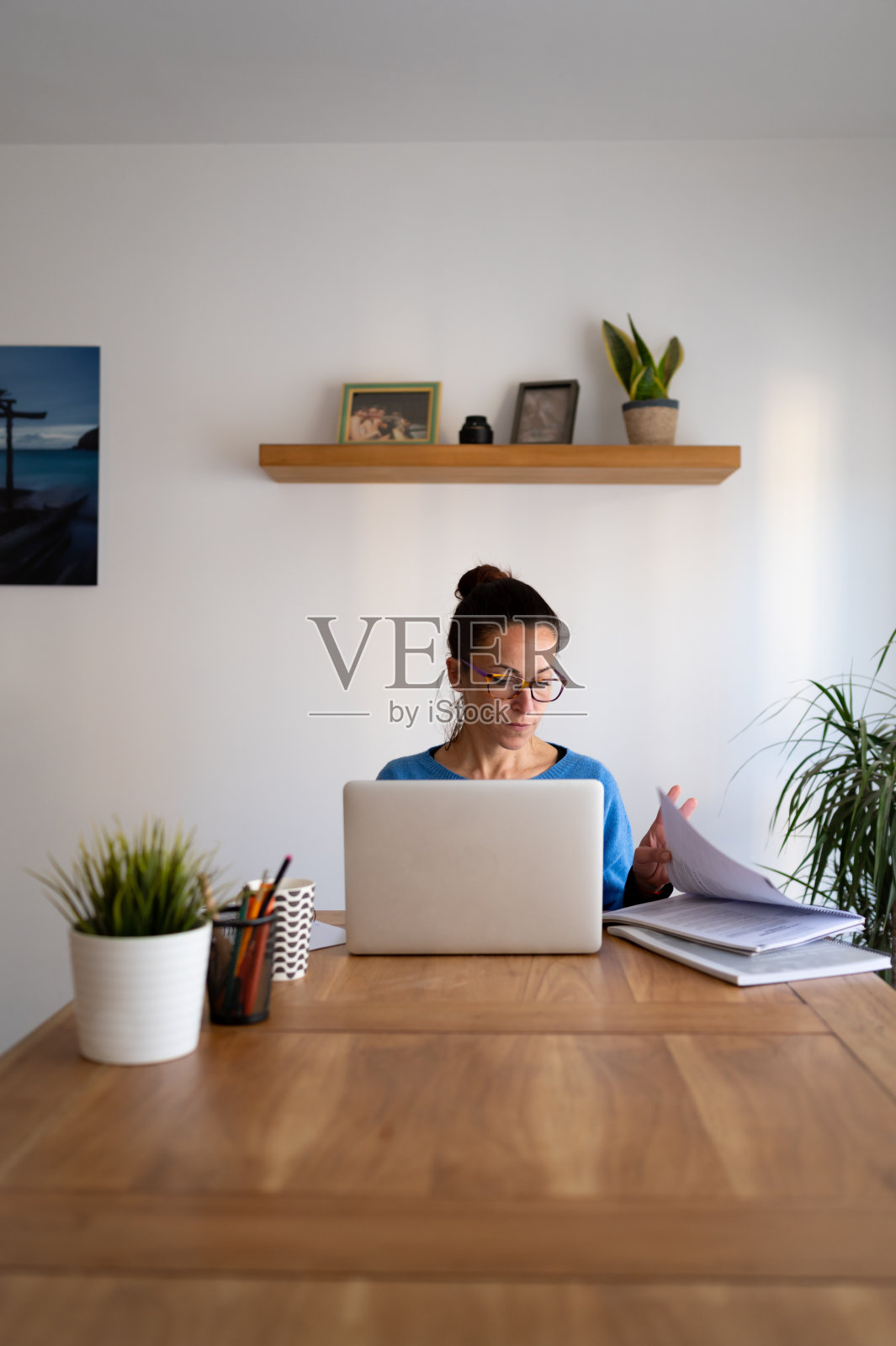 前视图的白人黑发妇女在家里工作在她的笔记本电脑。照片摄影图片