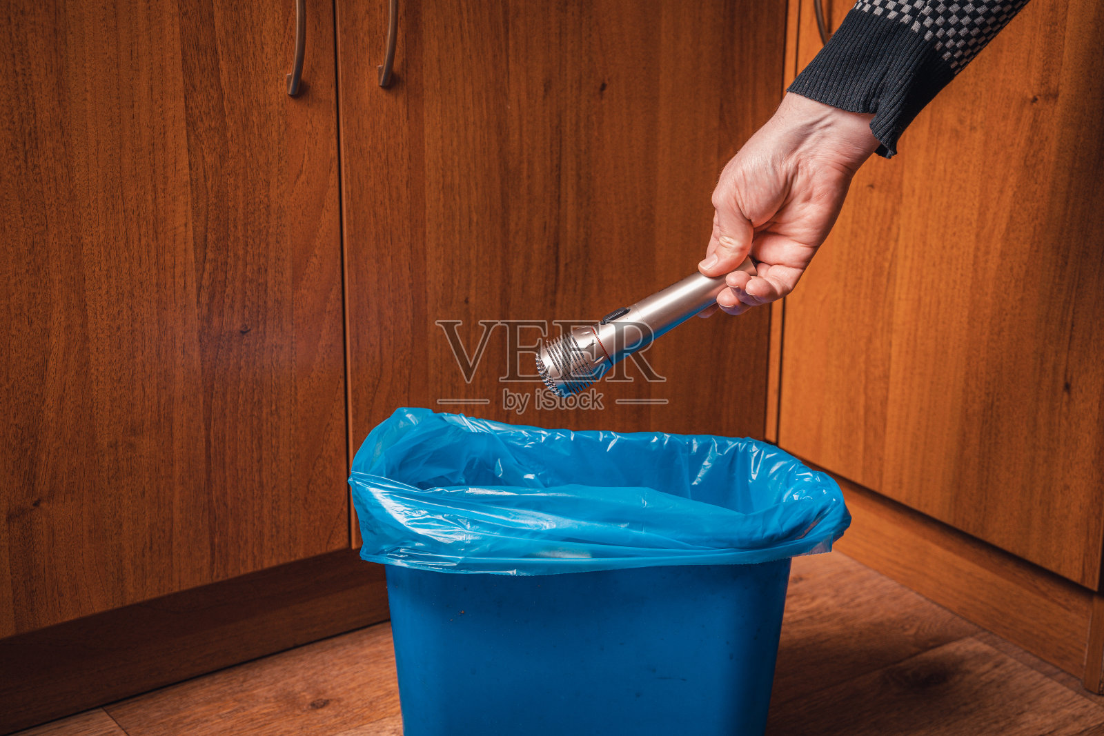 男人把麦克风扔进了垃圾桶。拿着麦克风和蓝色垃圾桶的男人的手。照片摄影图片