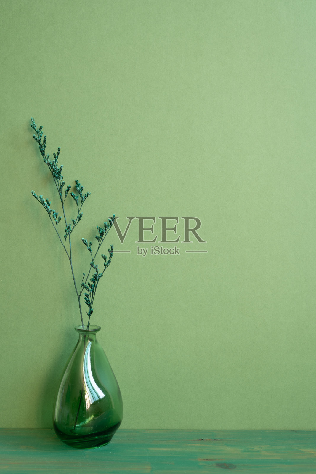 木桌上的干花玻璃花瓶。绿色墙壁背景。家居内部，简约，复制空间照片摄影图片