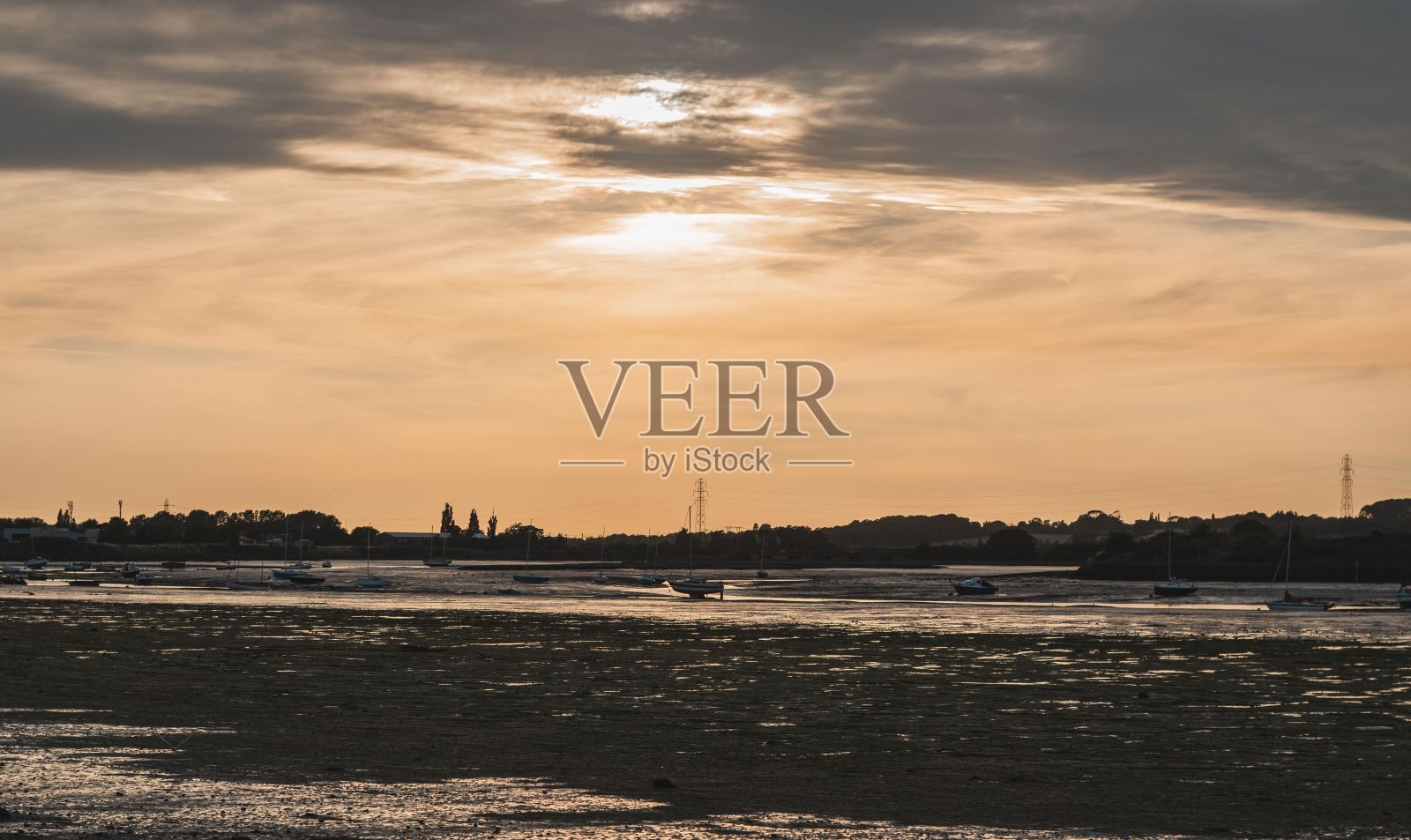 日落时分，海边的船只，背景是橙色多云的天空照片摄影图片