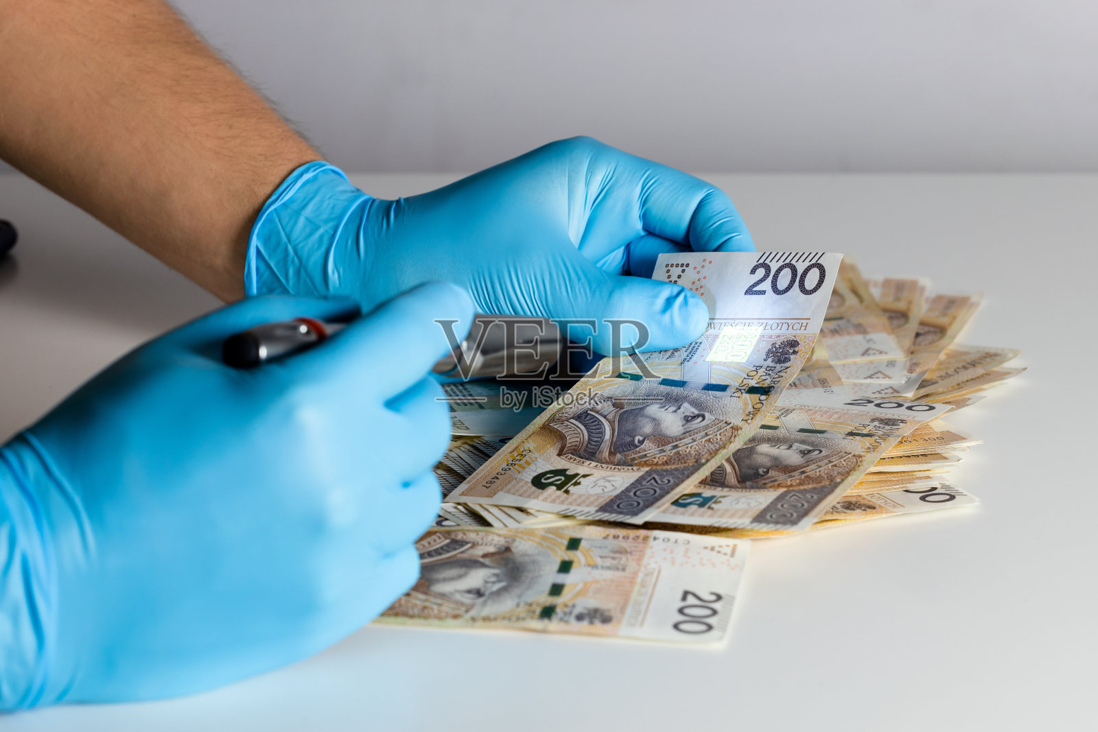 用紫外线灯检查假币。假的波兰200兹罗提钞票照片摄影图片