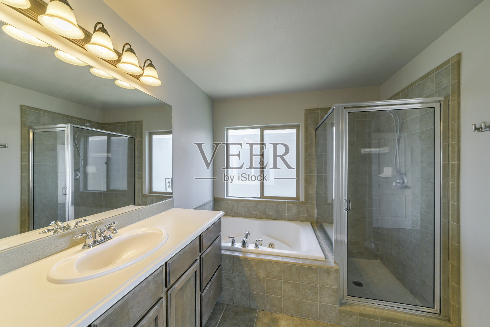 浴室里有按摩浴缸、淋浴浴缸和水槽，墙壁是灰色的照片摄影图片