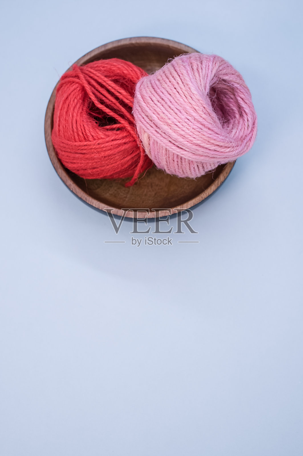 红色和粉红色的纱线编织在一个木碗上的蓝色背景的俯视图照片摄影图片