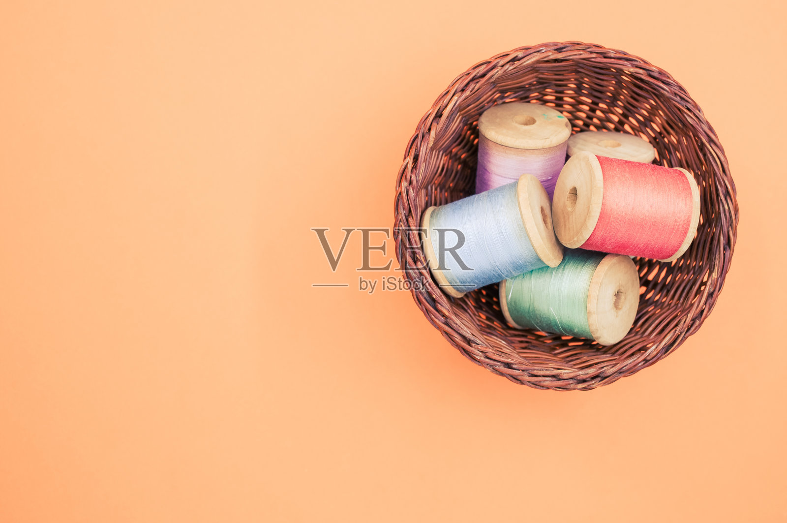 篮子的彩色缝纫线孤立在一个柔和的橙色背景与文本的自由空间照片摄影图片