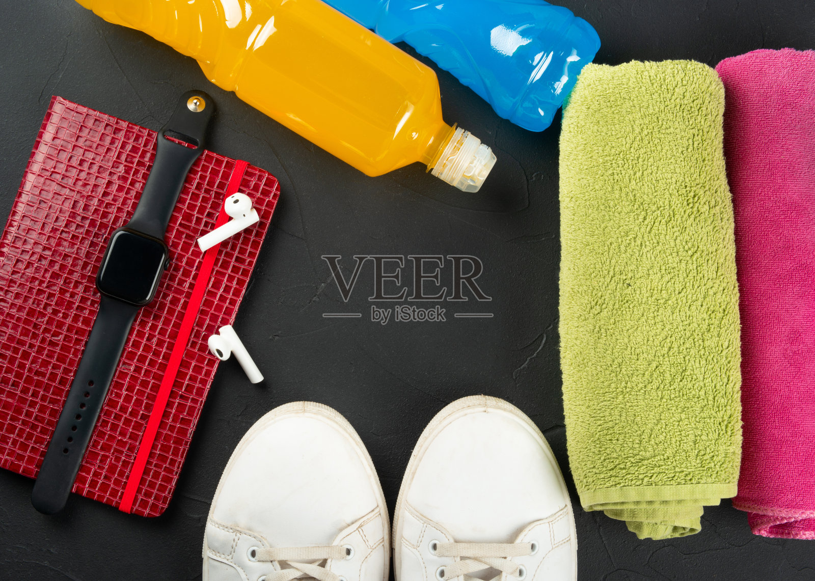 健康的概念。毛巾，运动鞋，一瓶等张饮料，记事本，智能手表，黑色混凝土背景上的卷尺，俯视图。本空间照片摄影图片