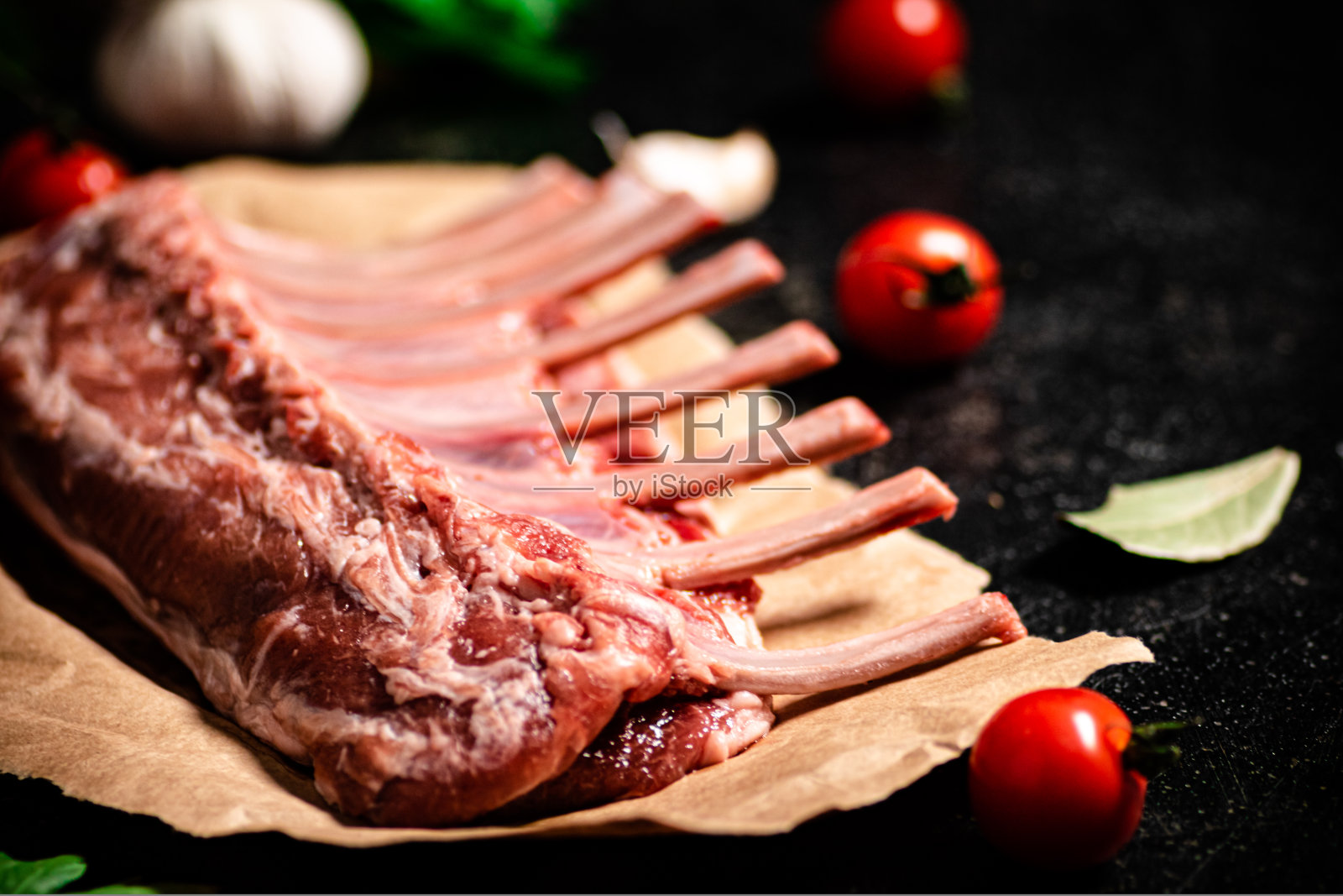 生羊排配大蒜，西红柿和月桂叶。照片摄影图片