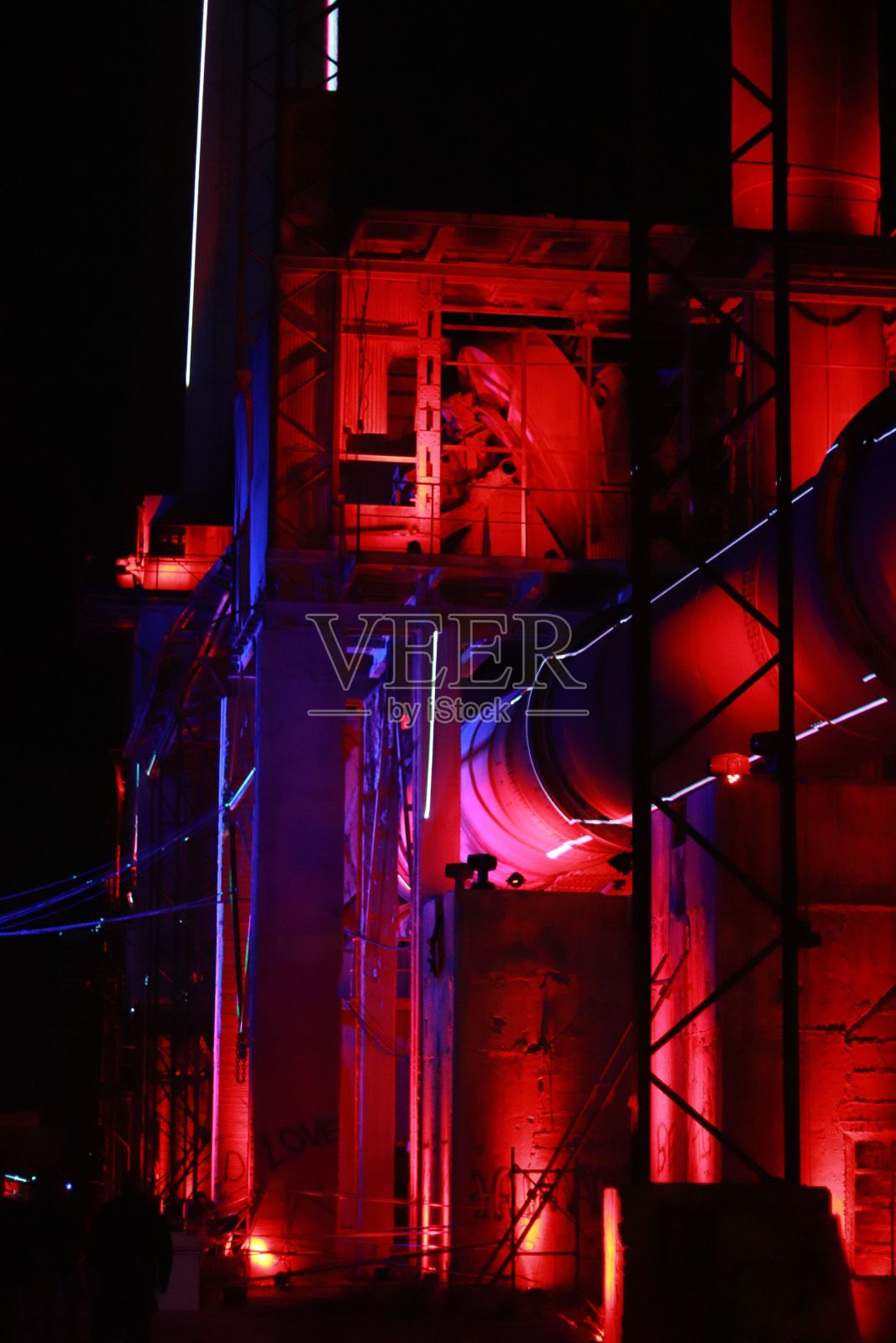 垂直拍摄的夜间工业建筑被霓虹灯的蓝色和红色照明照片摄影图片