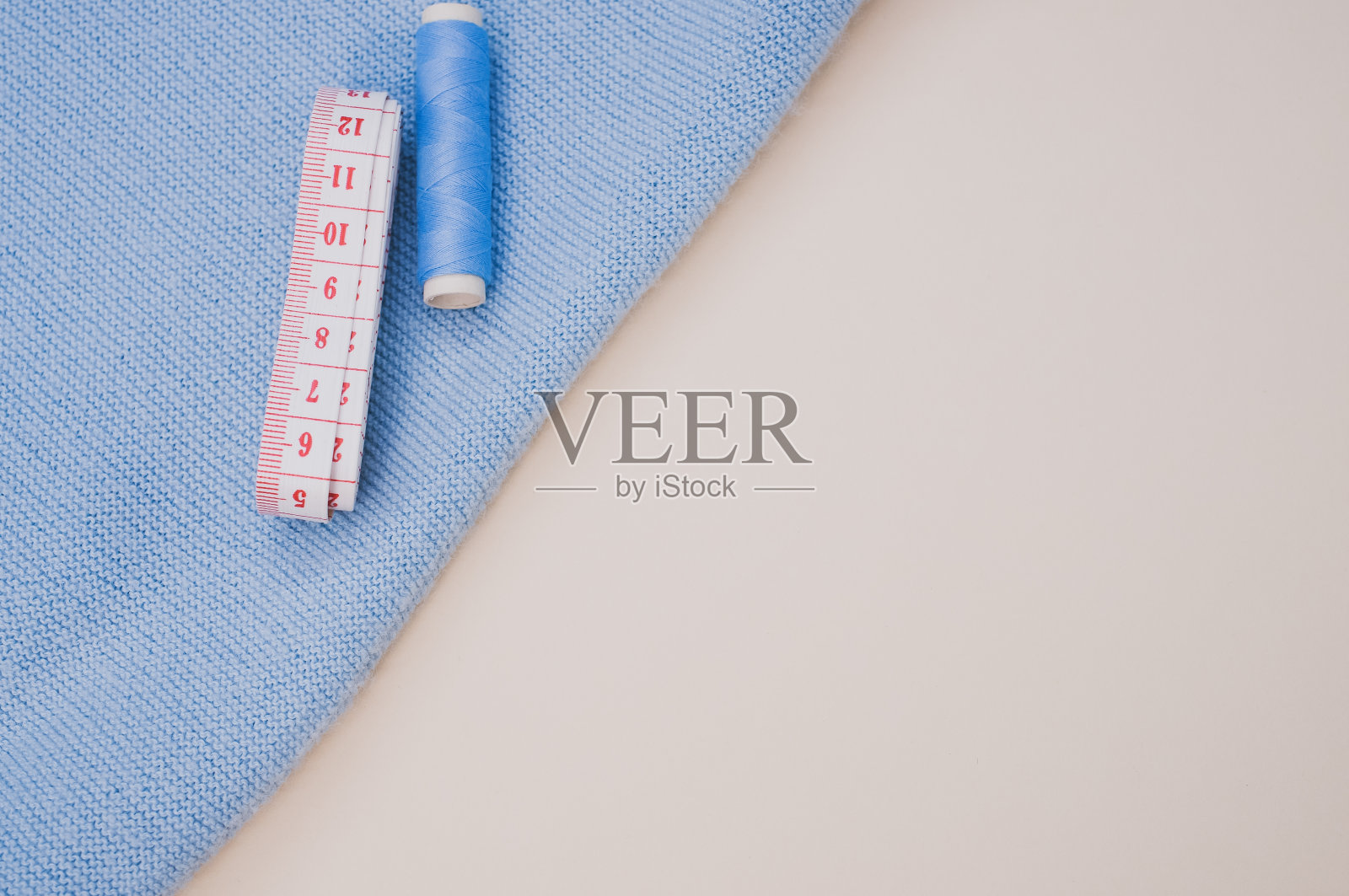 俯视图的蓝色缝纫线和测量卷尺在织物上的棕色表面照片摄影图片