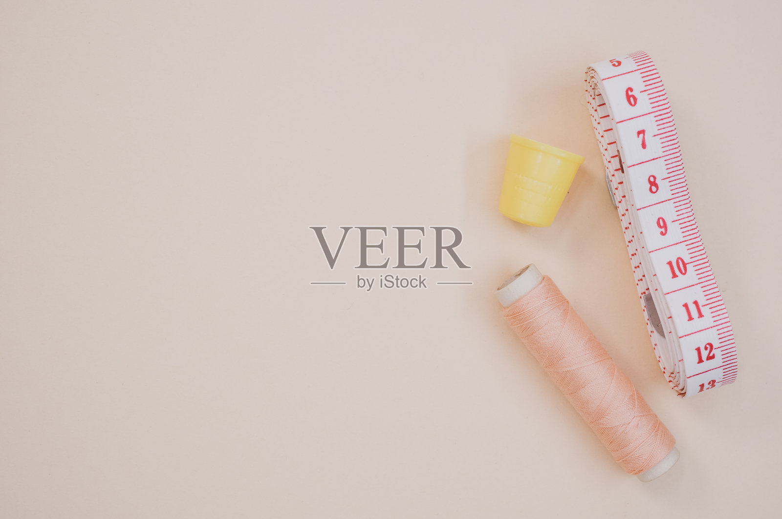 顶部视图的粉红色缝纫线与顶针和测量带在棕色表面照片摄影图片