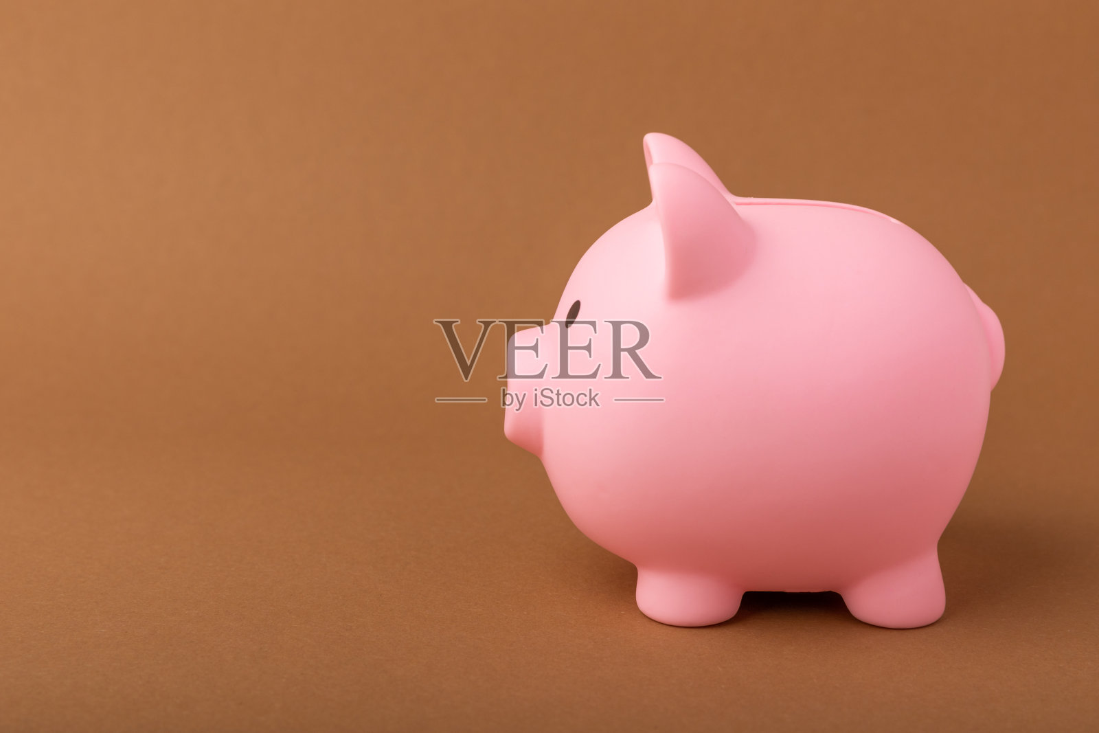 棕色纹理背景上的小猪储蓄罐。发短信的地方。本空间照片摄影图片