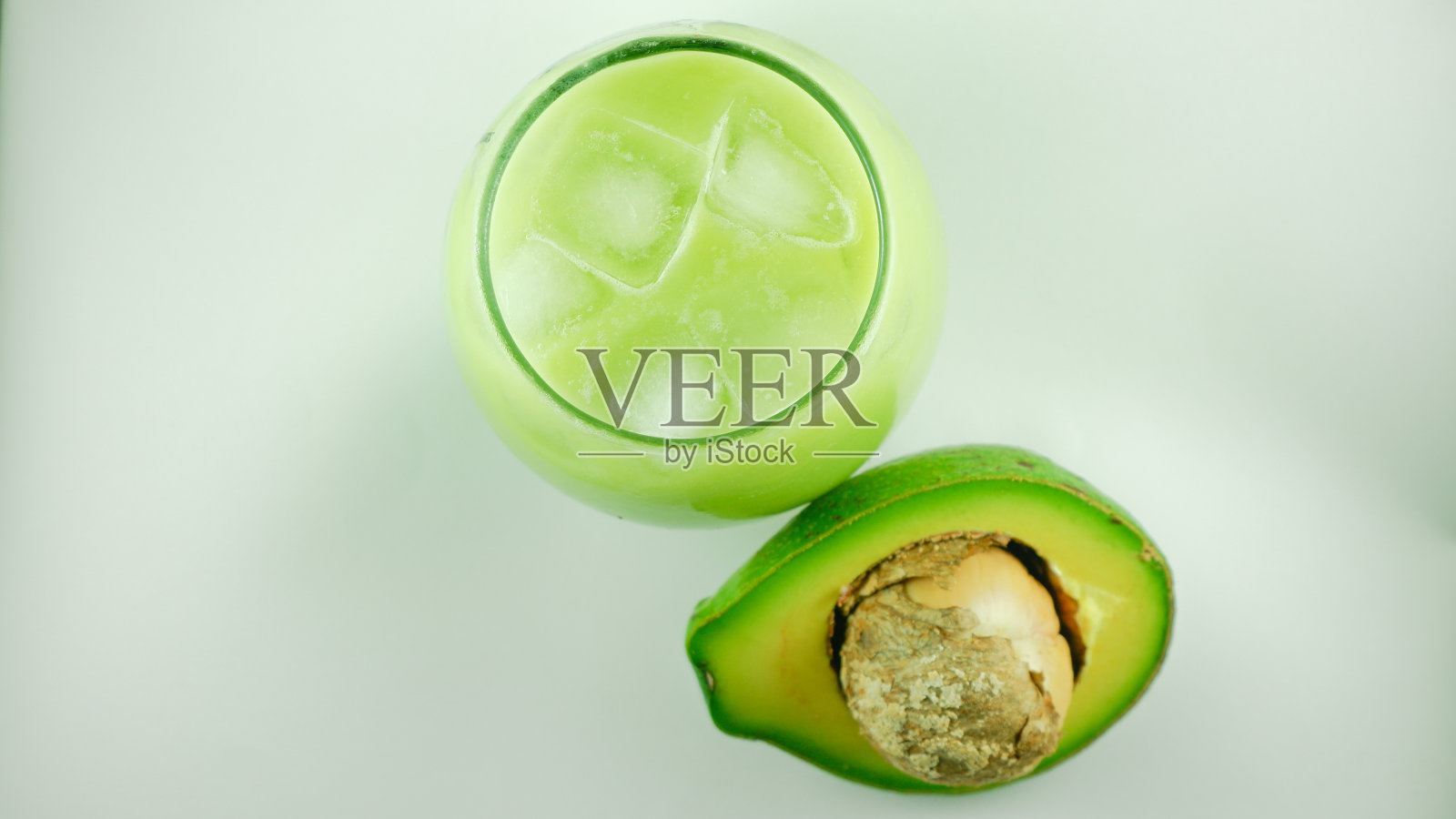 白底透明玻璃杯中的牛油果和牛油果汁照片摄影图片