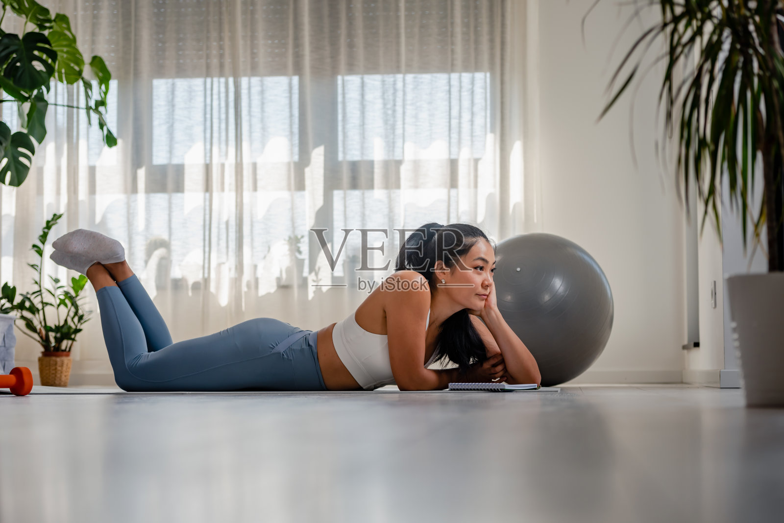 年轻的亚洲瑜伽女在她的笔记本上写着。运动后坐在家里的窗边。个人成长计划照片摄影图片