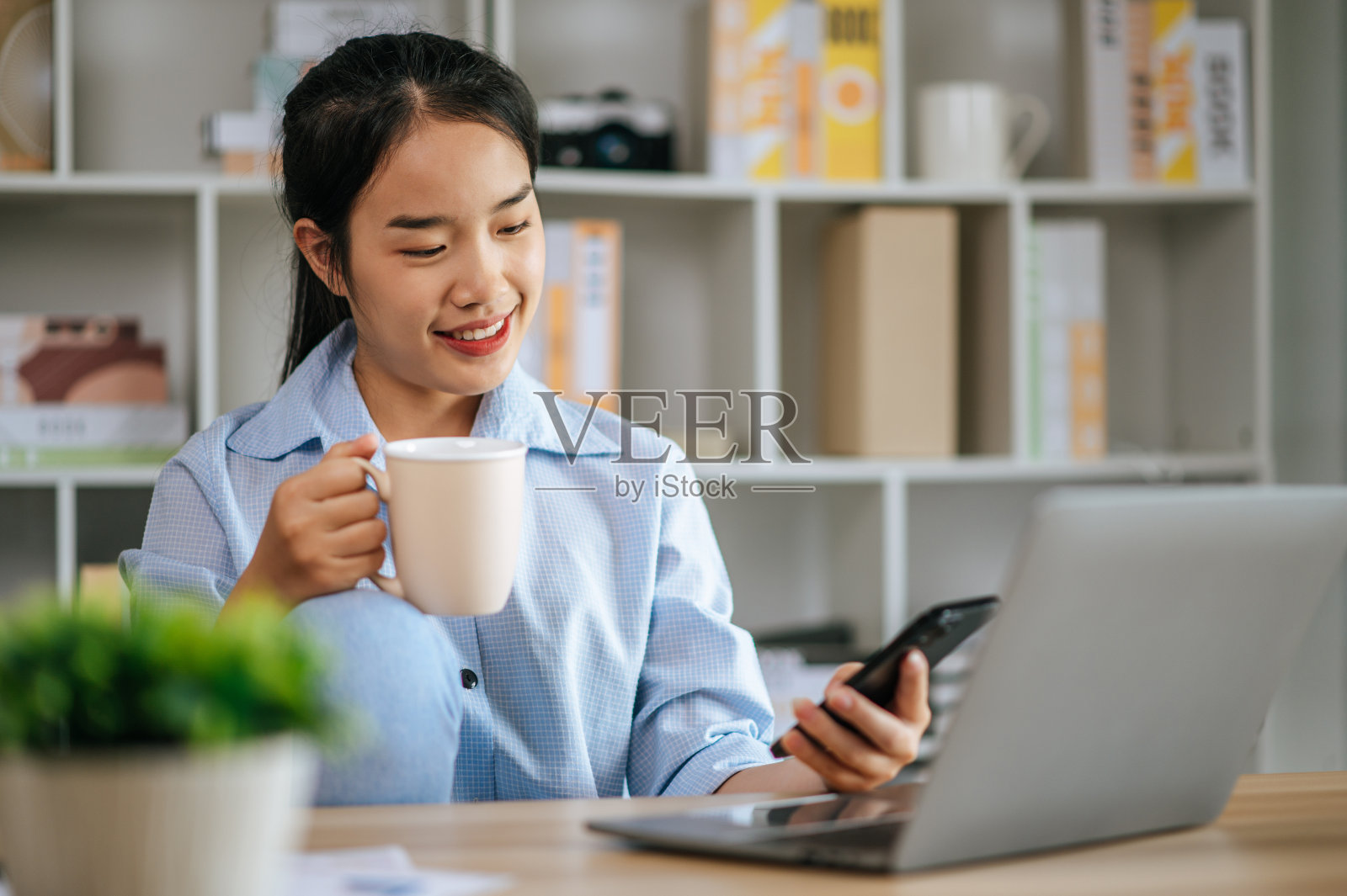 年轻女子在家里用笔记本电脑和智能手机工作照片摄影图片