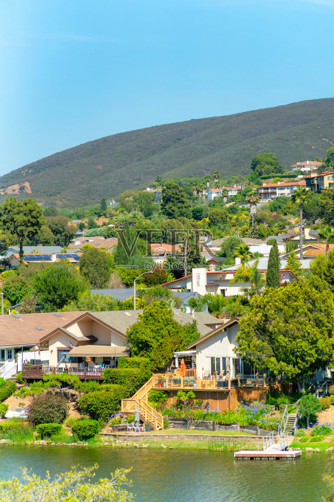 垂直拍摄的一个小镇，有住宅和一条被山丘包围的河流照片摄影图片